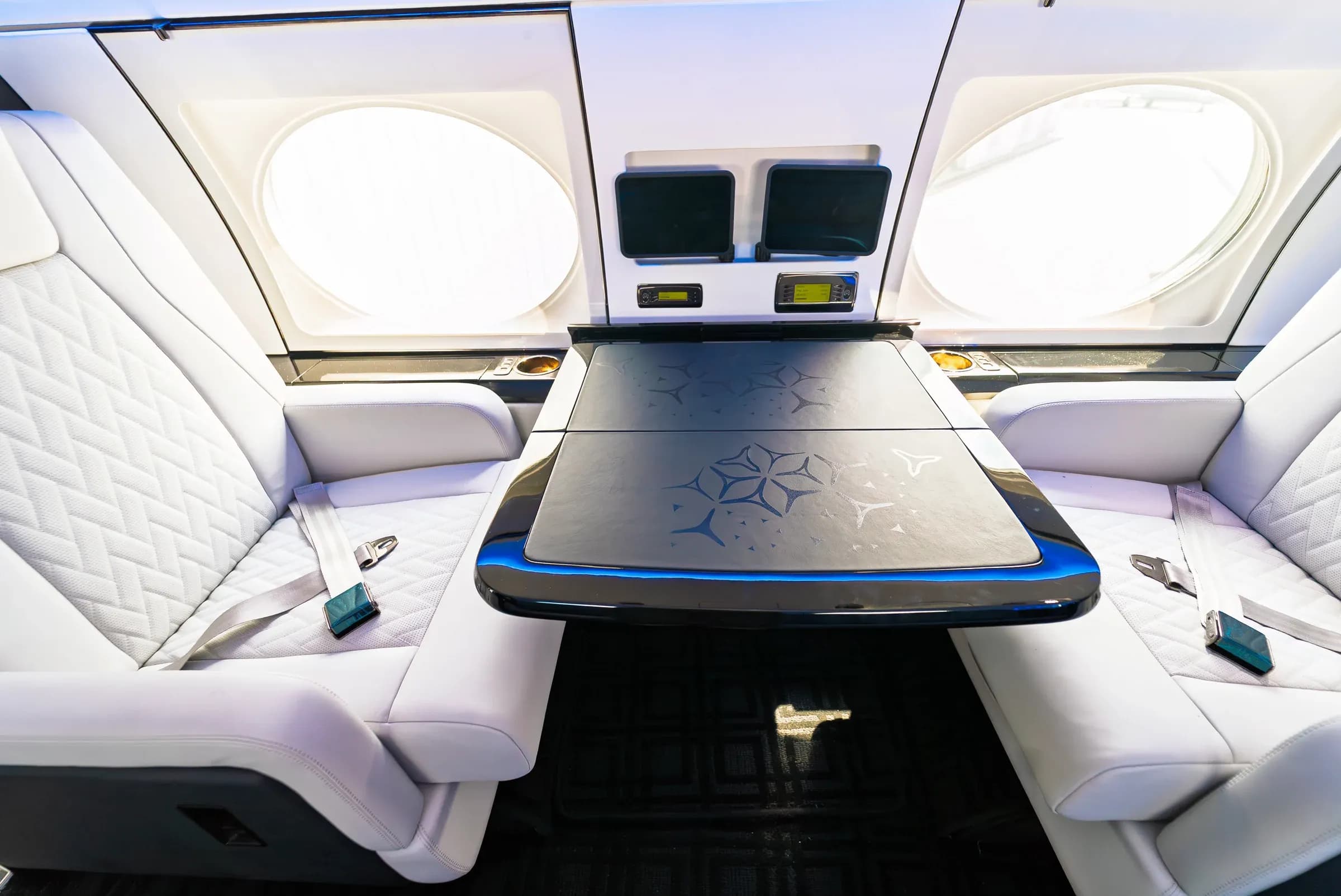 Gulfstream G-IV cabin table with geometric detailing, white seats and blue edge lighting.