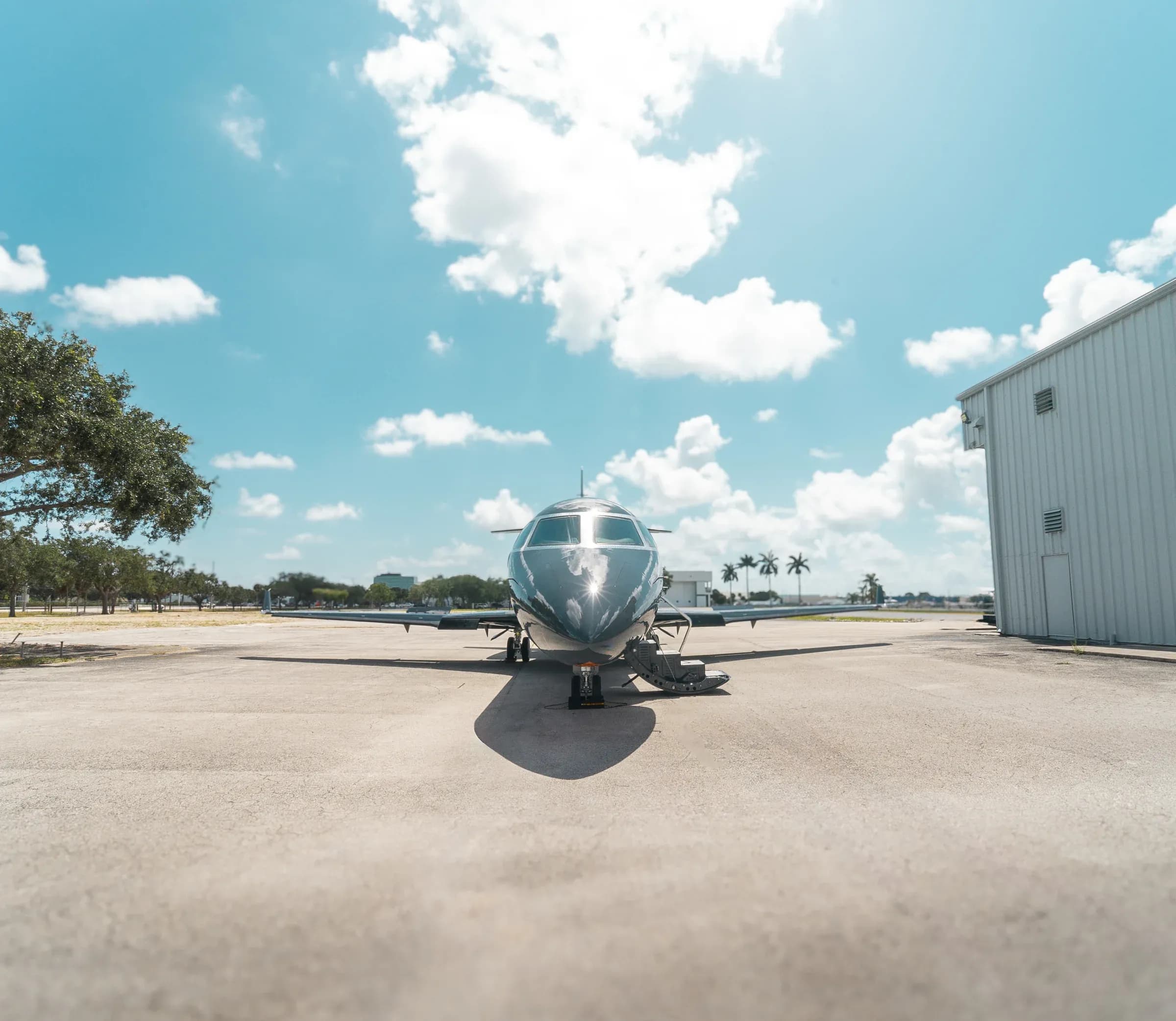Frontal view of the Gulfstream G200 on the ramp beside airport hangars.