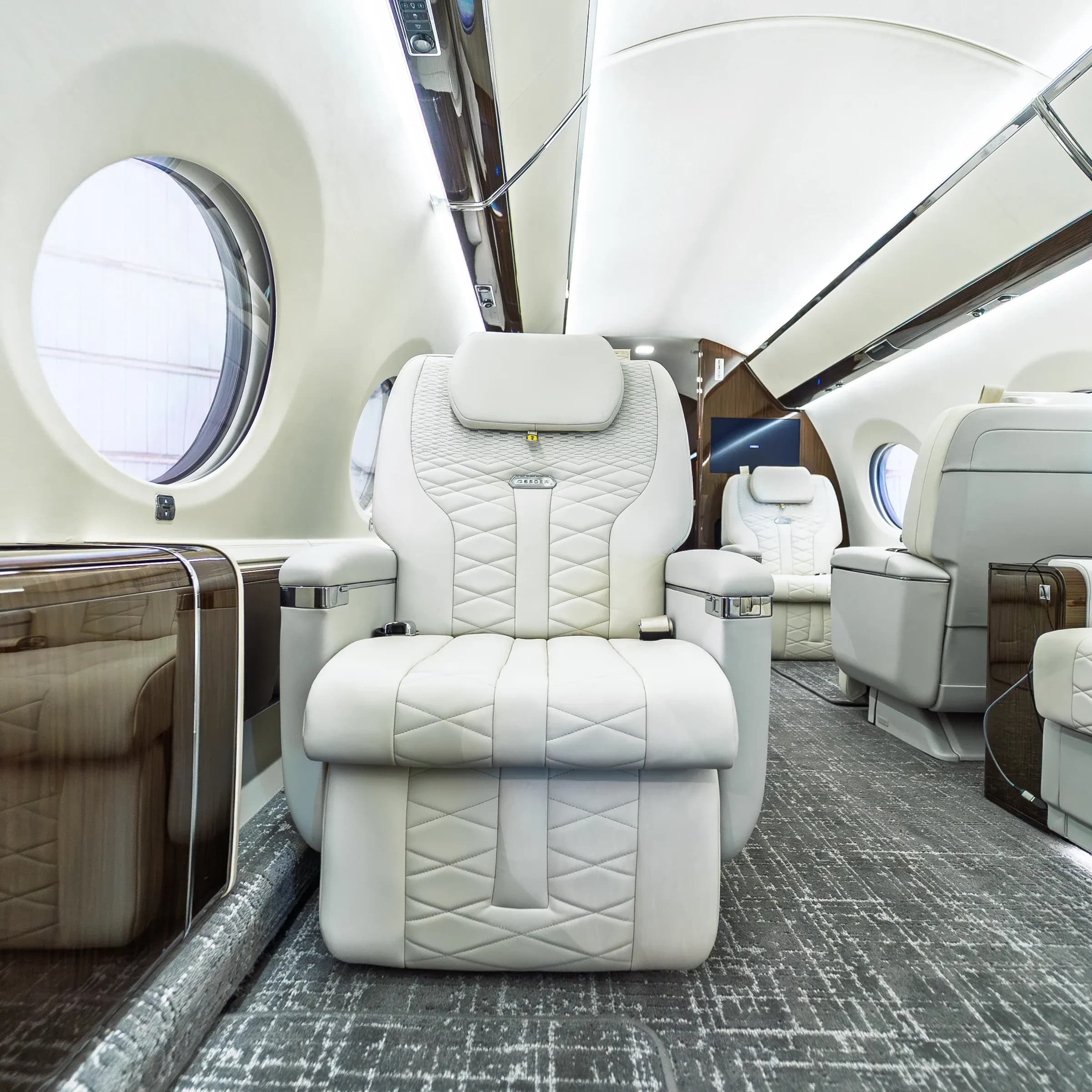 Frontal view of an ivory Gulfstream G650ER chair with diamond quilting and a metal backrest badge.