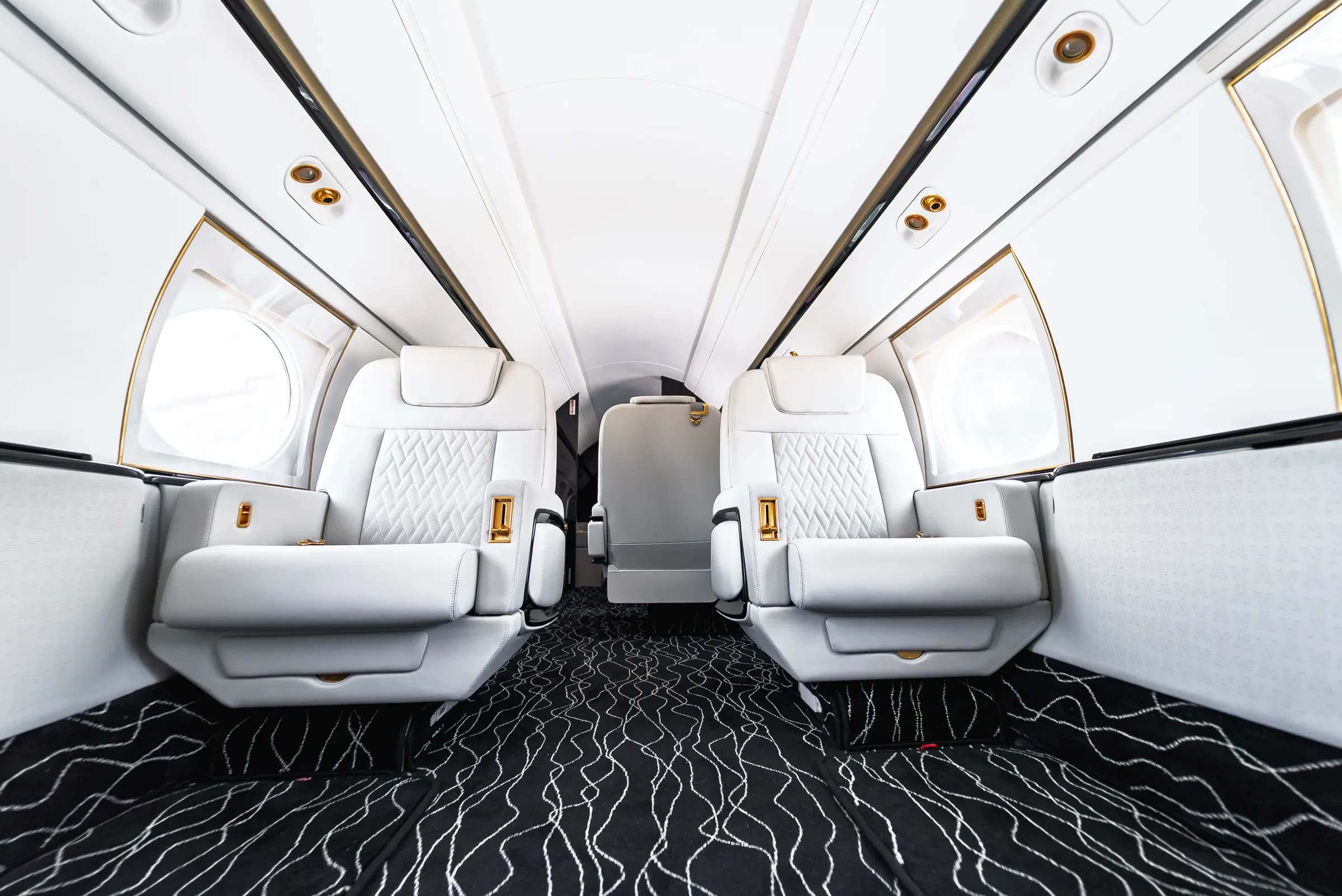 Low view of white Gulfstream G550 seats and the wavy patterned cabin carpet.