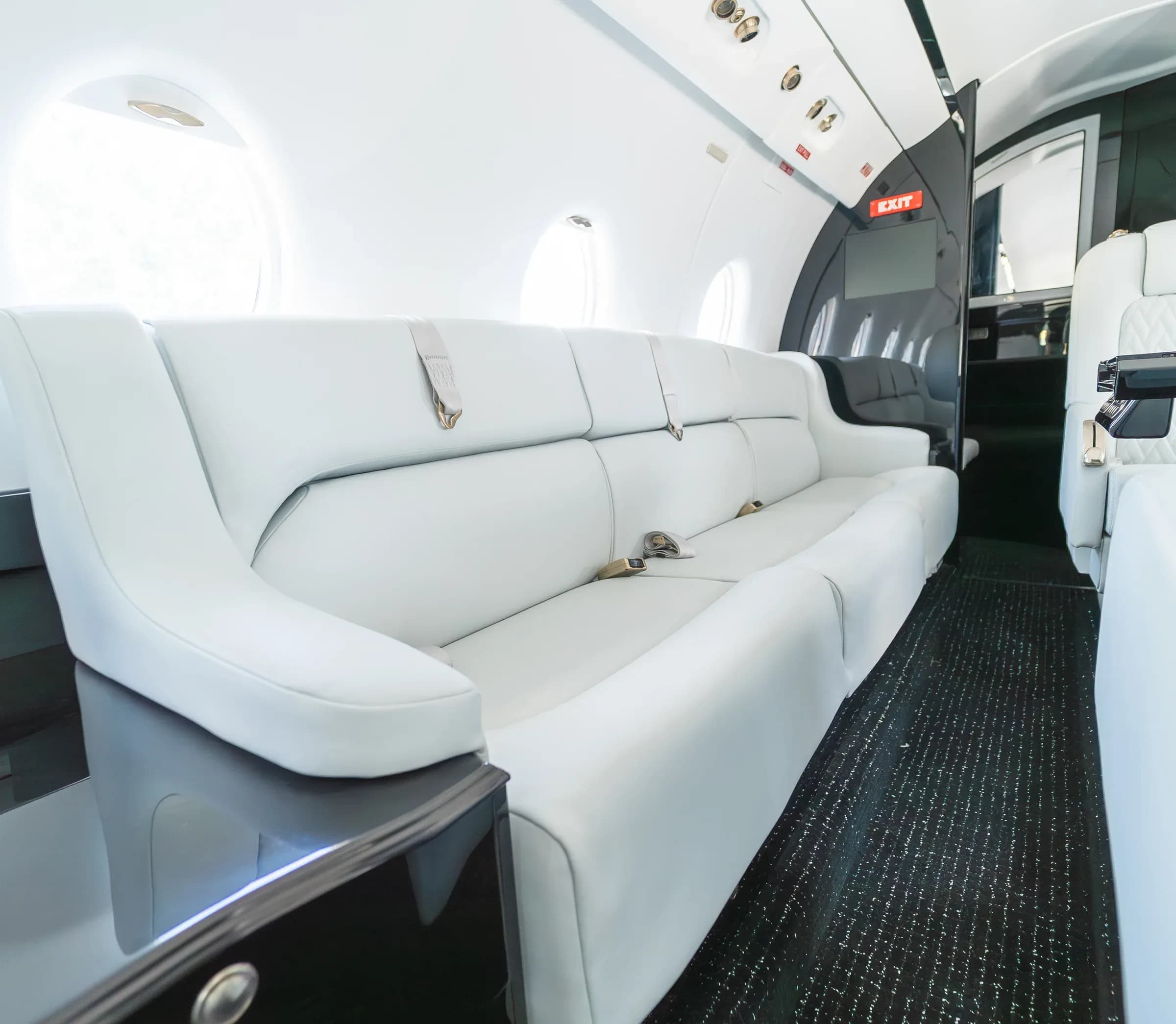 White upholstered divan with seat belts and dark cabinetry in the Gulfstream G200 cabin.