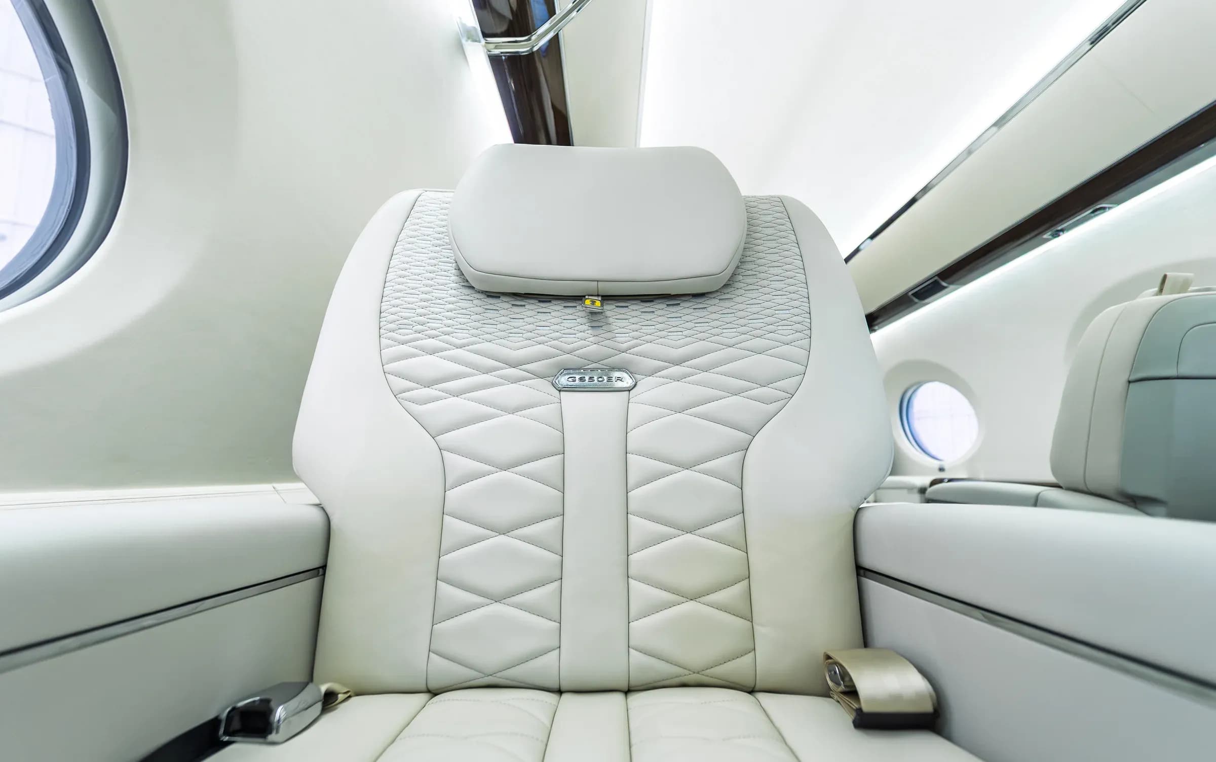 Close view of the Gulfstream G650ER headrest, diamond stitching and metal backrest badge.