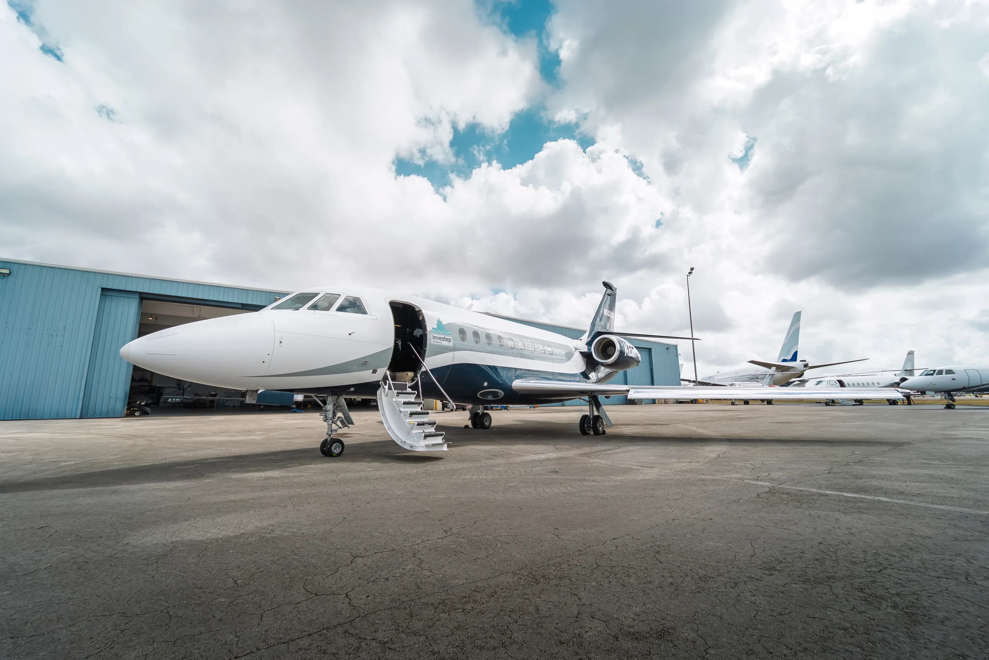 Front three-quarter view of the Falcon 2000 on the apron beside the hangar.