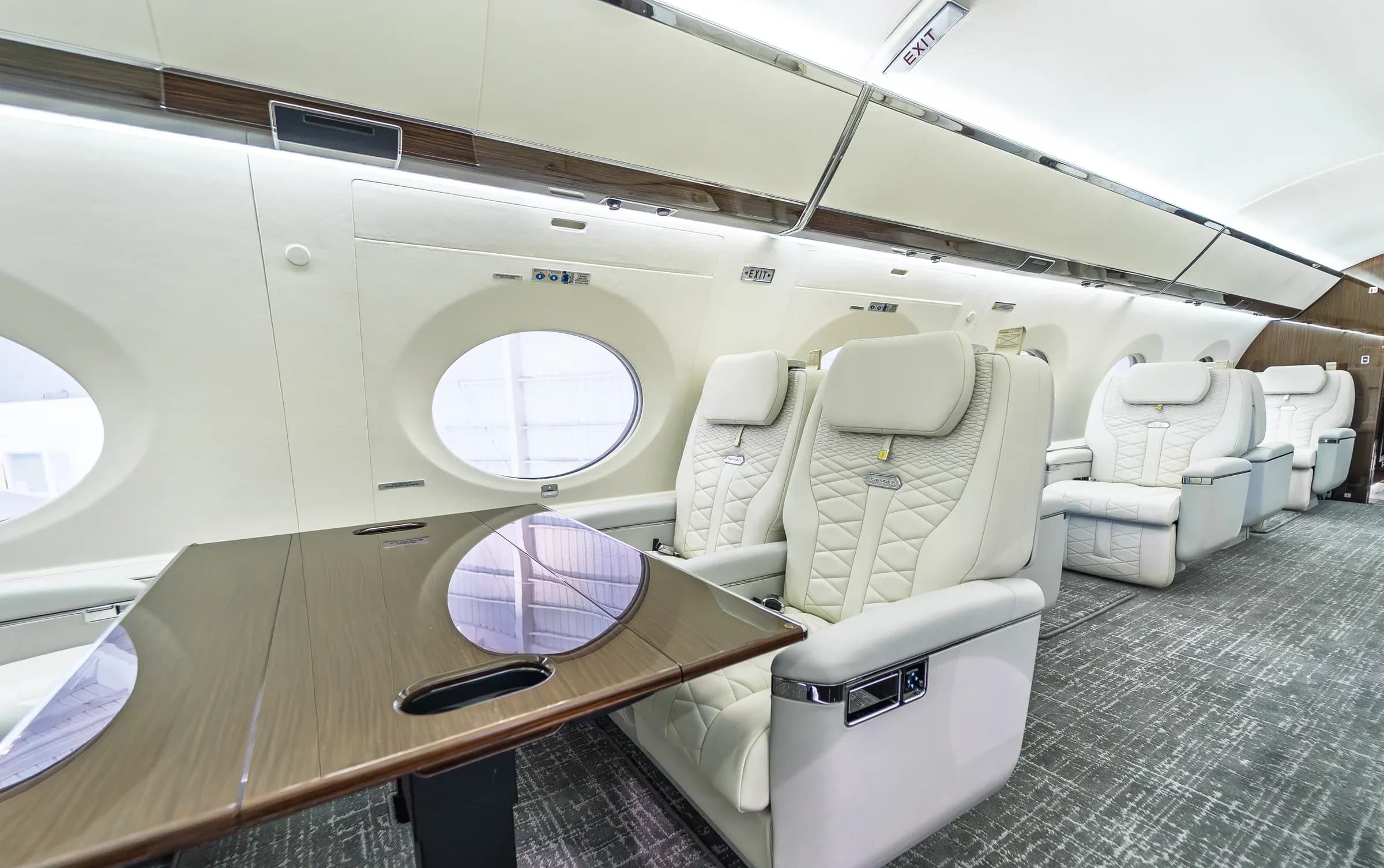 Angled view of an ivory quilted Gulfstream G650ER chair beside the cabin table.