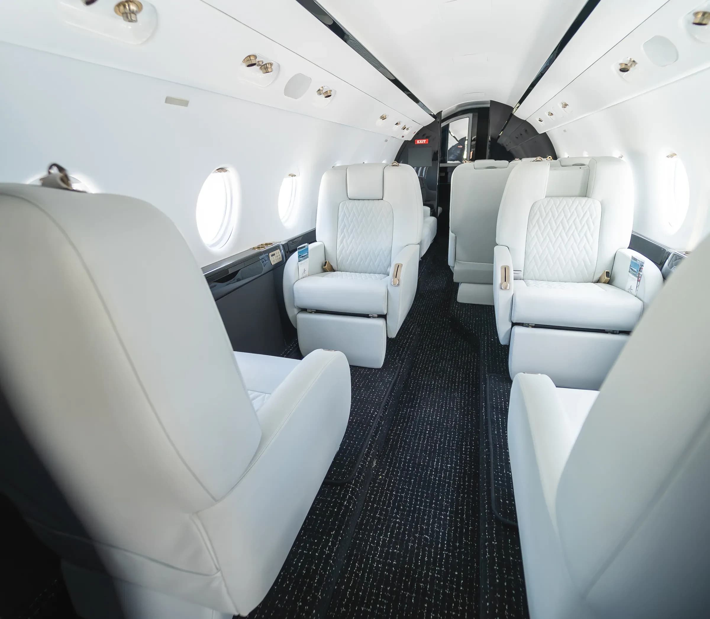 Centered view through the Gulfstream G200 cabin, with white diamond-quilted seats and dark carpet.
