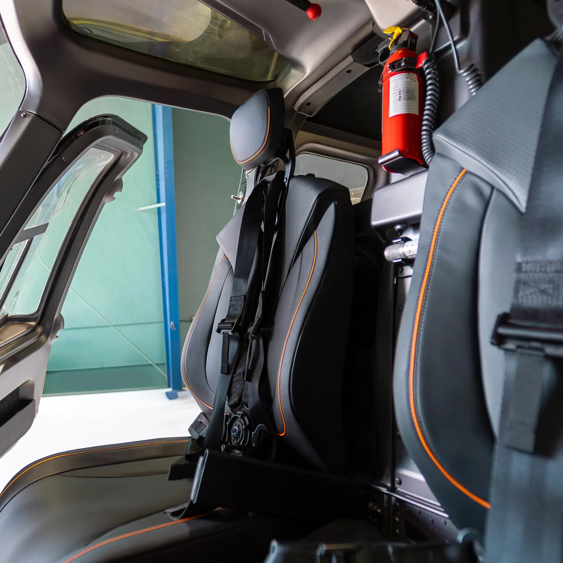 Bell 407 cockpit seat, belt and orange-edged upholstery beside the cabin equipment.