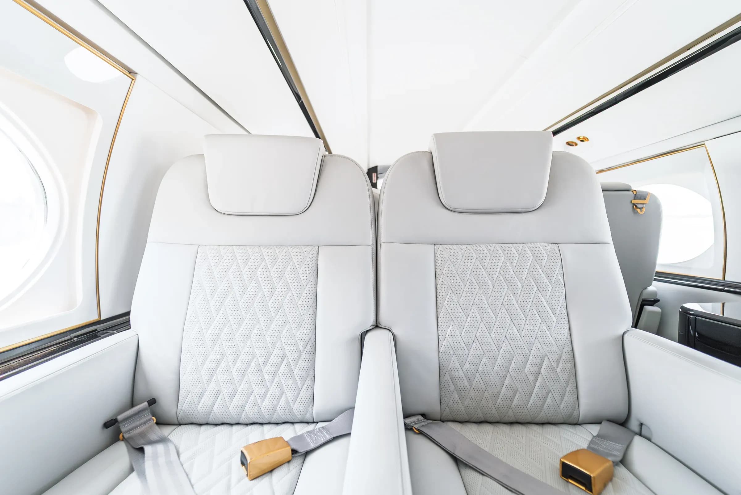 White Gulfstream G550 seat backs and quilted inserts with gold-tone belt fittings.