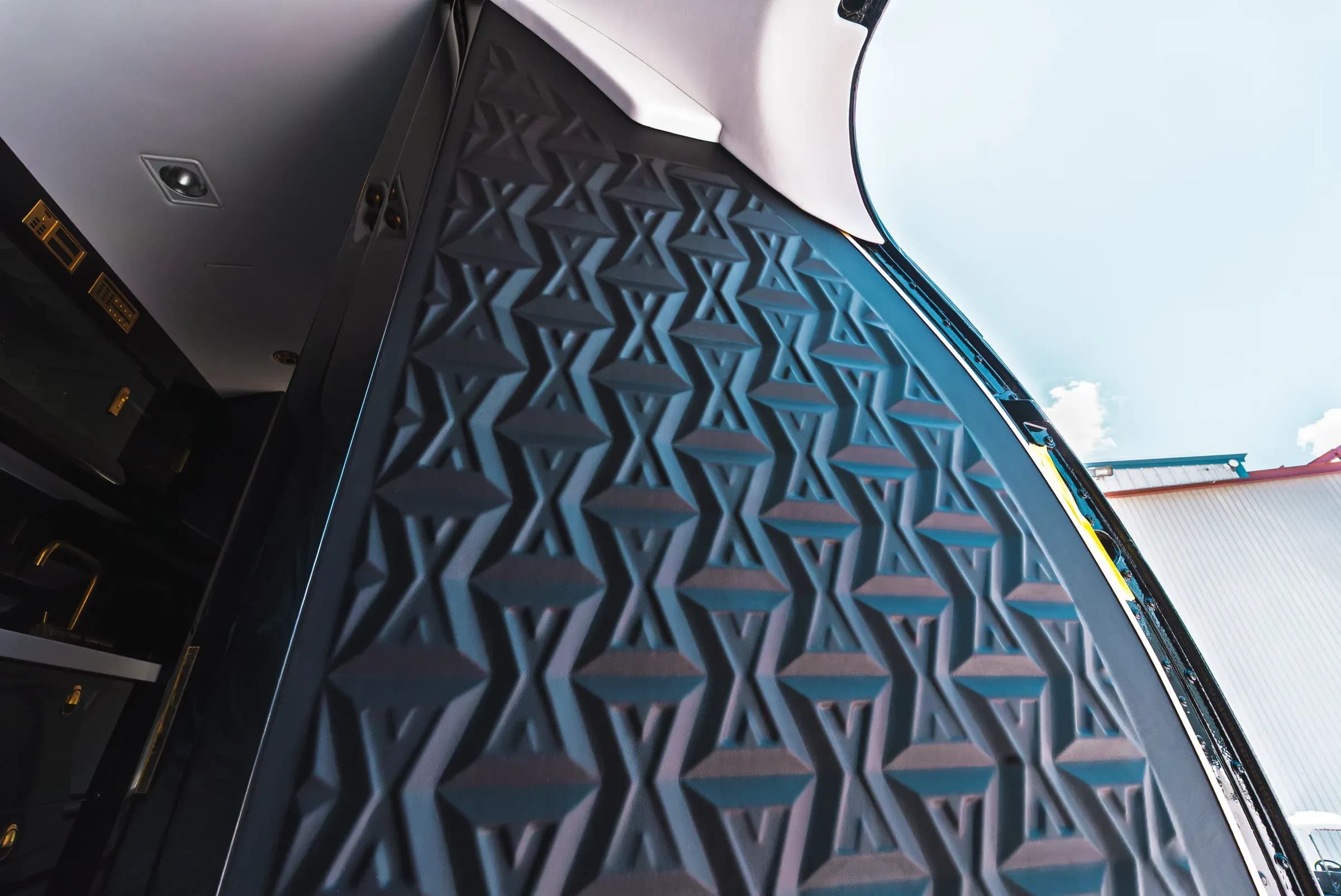 Low-angle detail of the repeating geometric relief on a Gulfstream G550 entrance panel.