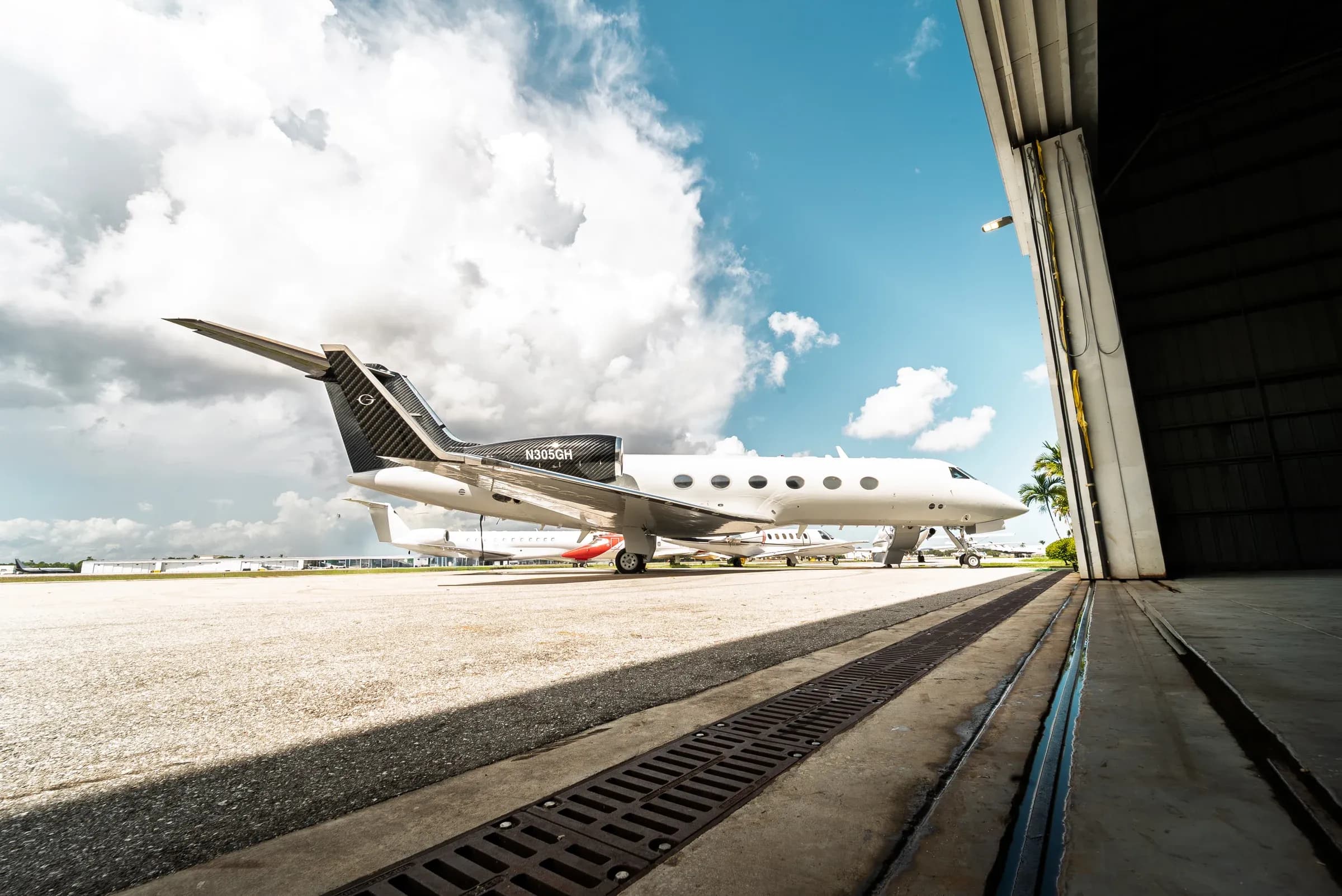 Low-angle exterior view of the white Gulfstream G-IV outside an aircraft hangar.