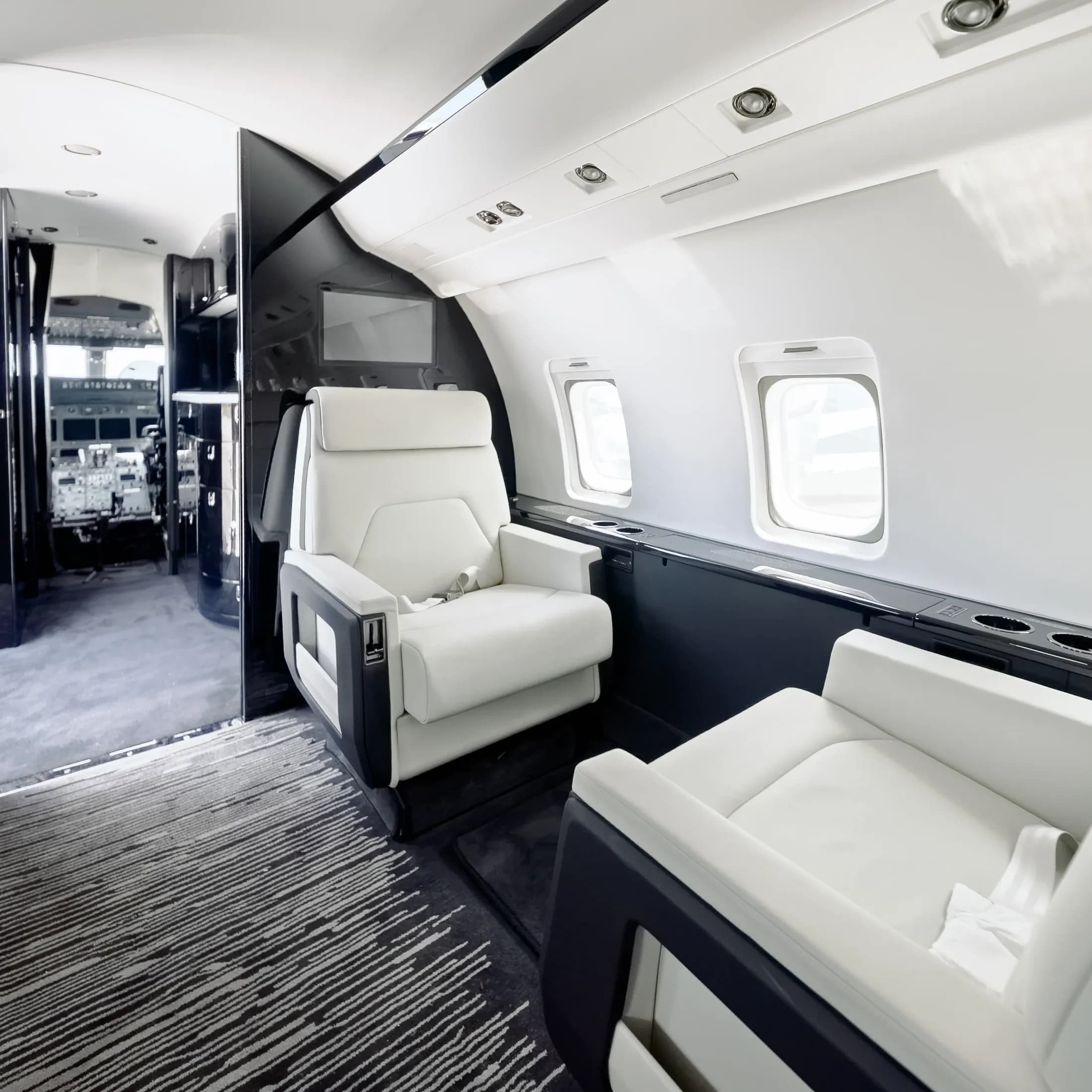 Challenger 604 lounge seating beside dark cabinetry and pale cabin sidewalls.