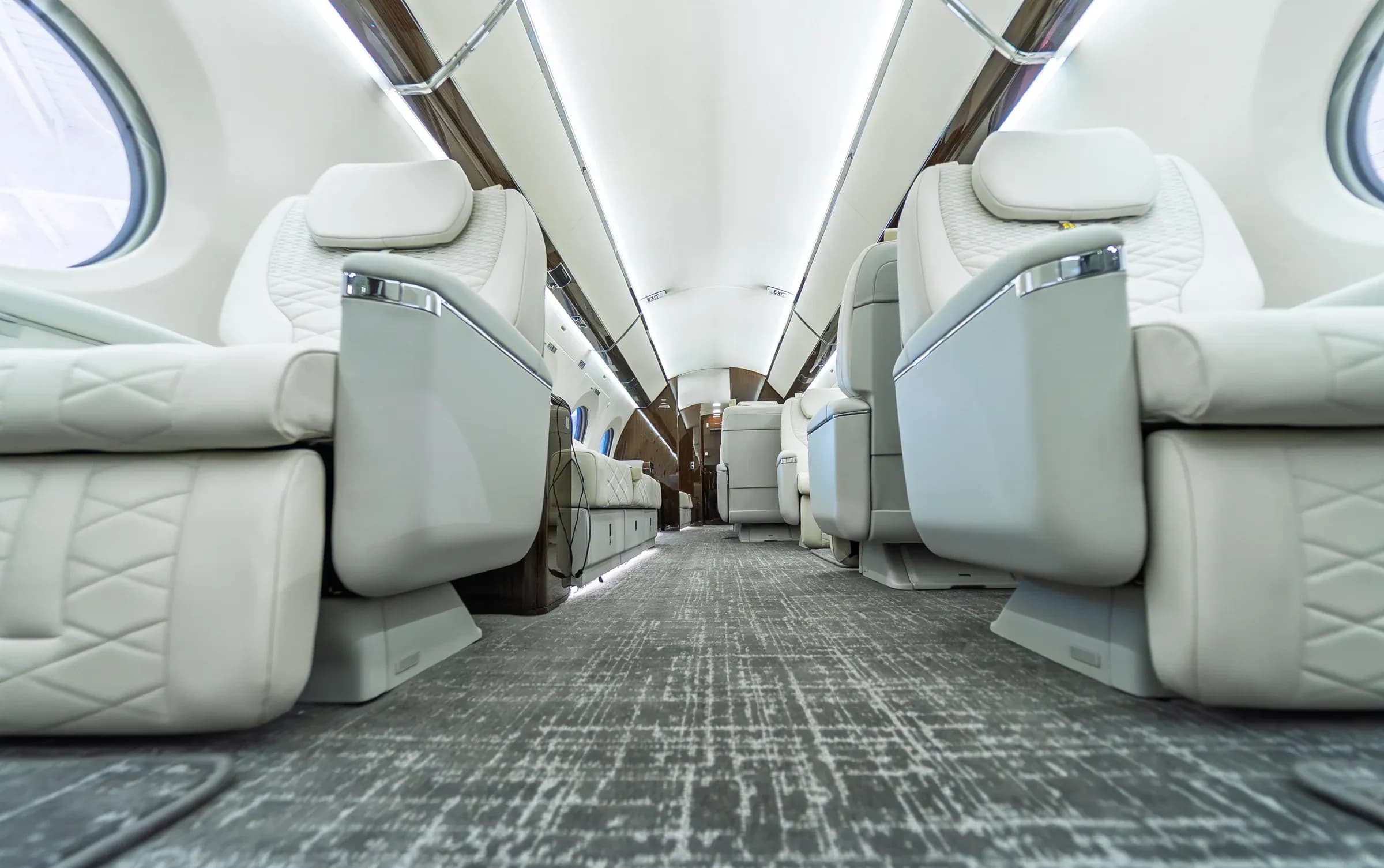 Floor-level view of Gulfstream G650ER seat bases and gray linear-patterned carpet.