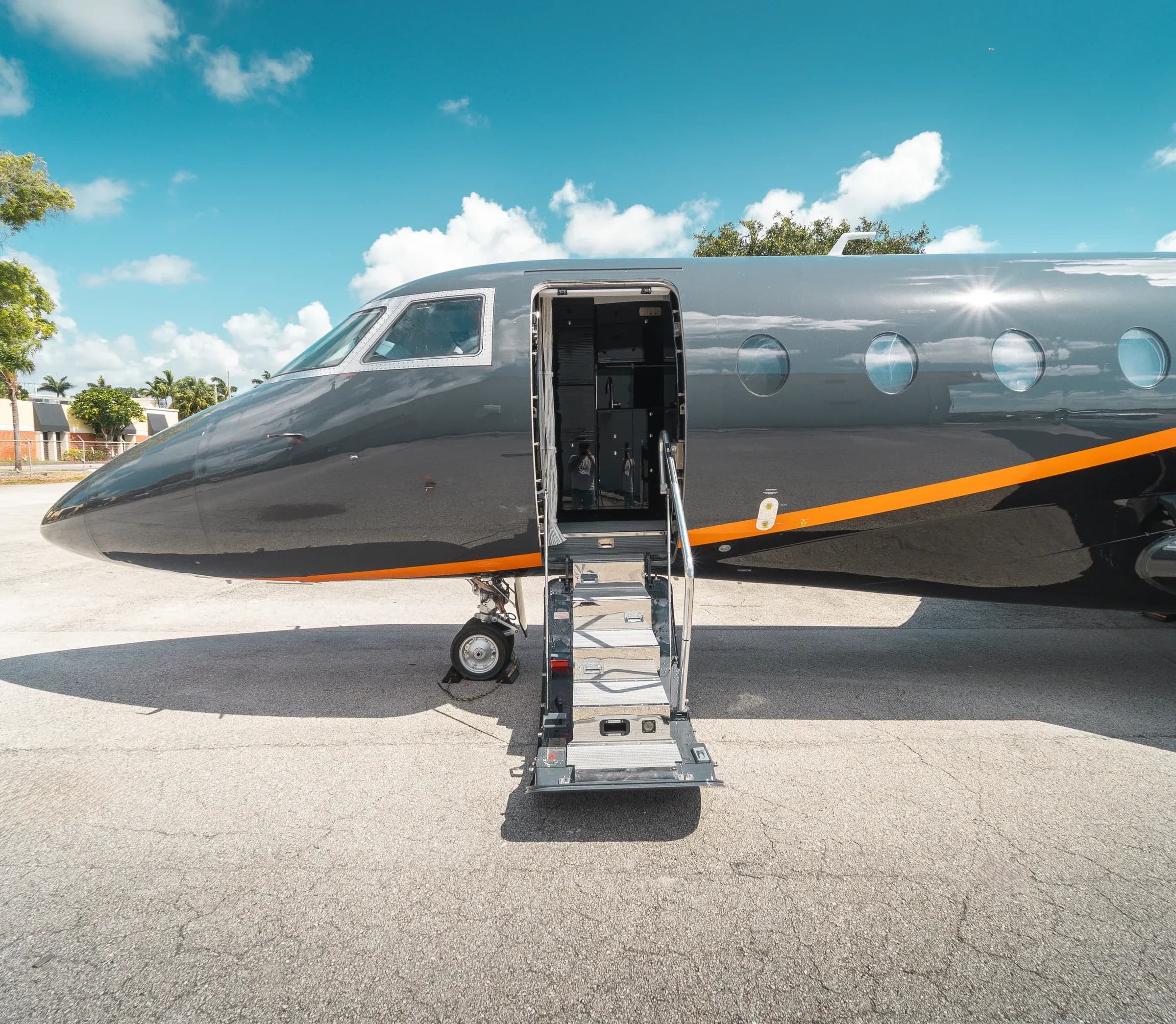 Gulfstream G200 nose and open entry stairs on the ramp under a blue sky.