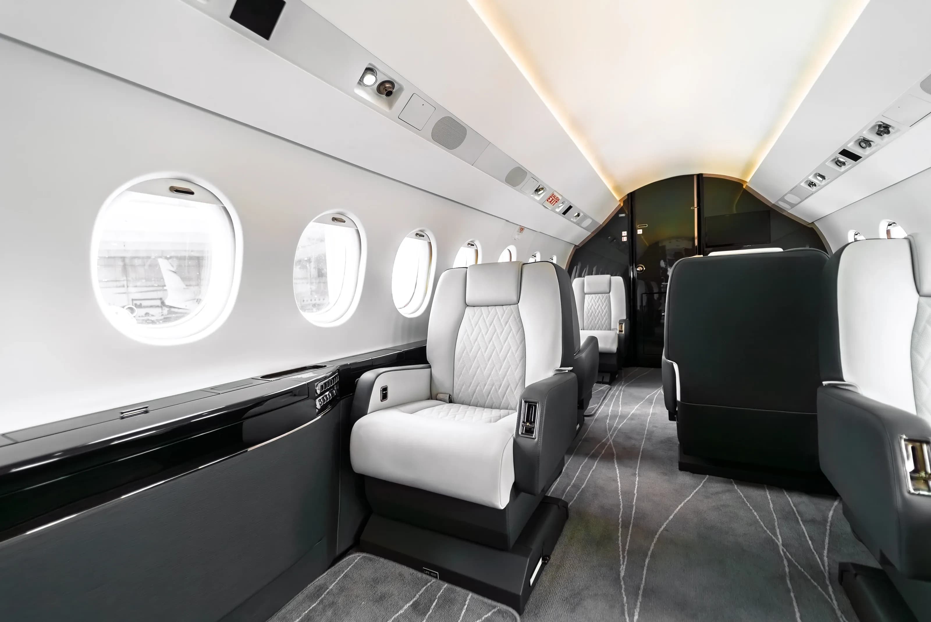 Falcon 2000 quilted seats and dark seat shells above the flowing linear-pattern carpet.