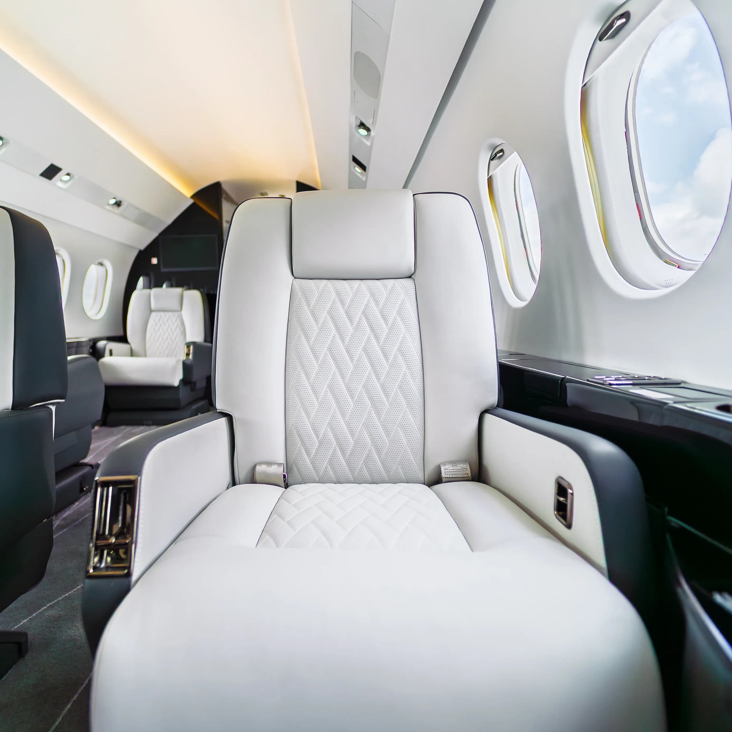 Falcon 2000 ivory seat with elongated diamond quilting beside the oval cabin windows.