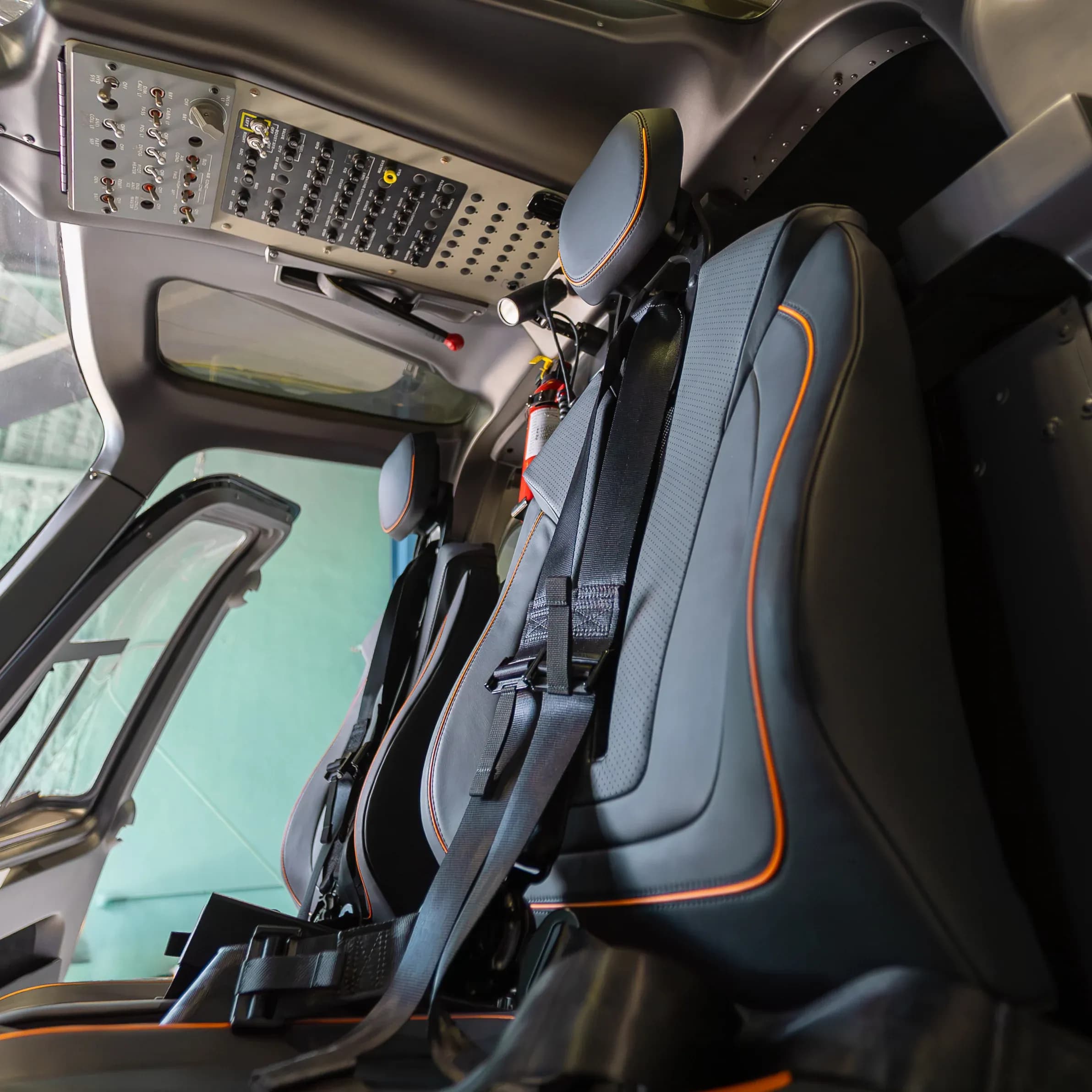 Angled view of the dark Bell 407 front seats with orange piping.