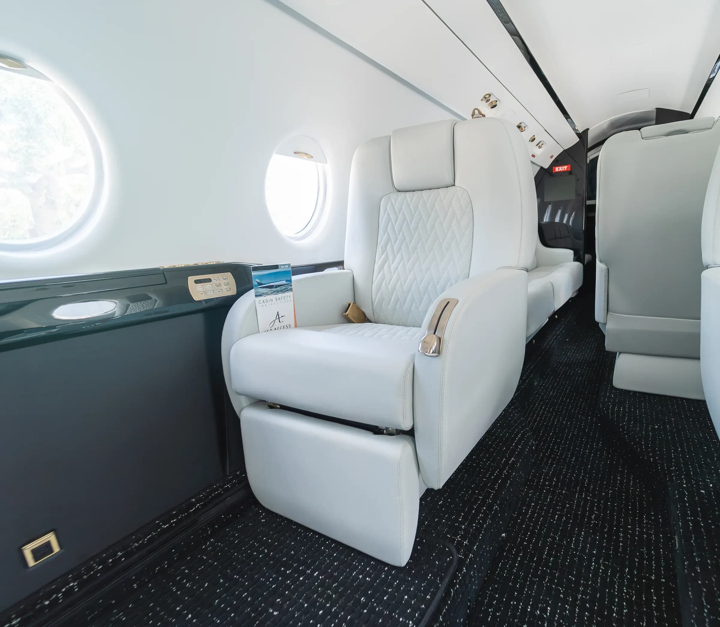 A white diamond-quilted Gulfstream G200 seat beside oval windows and a dark side ledge.
