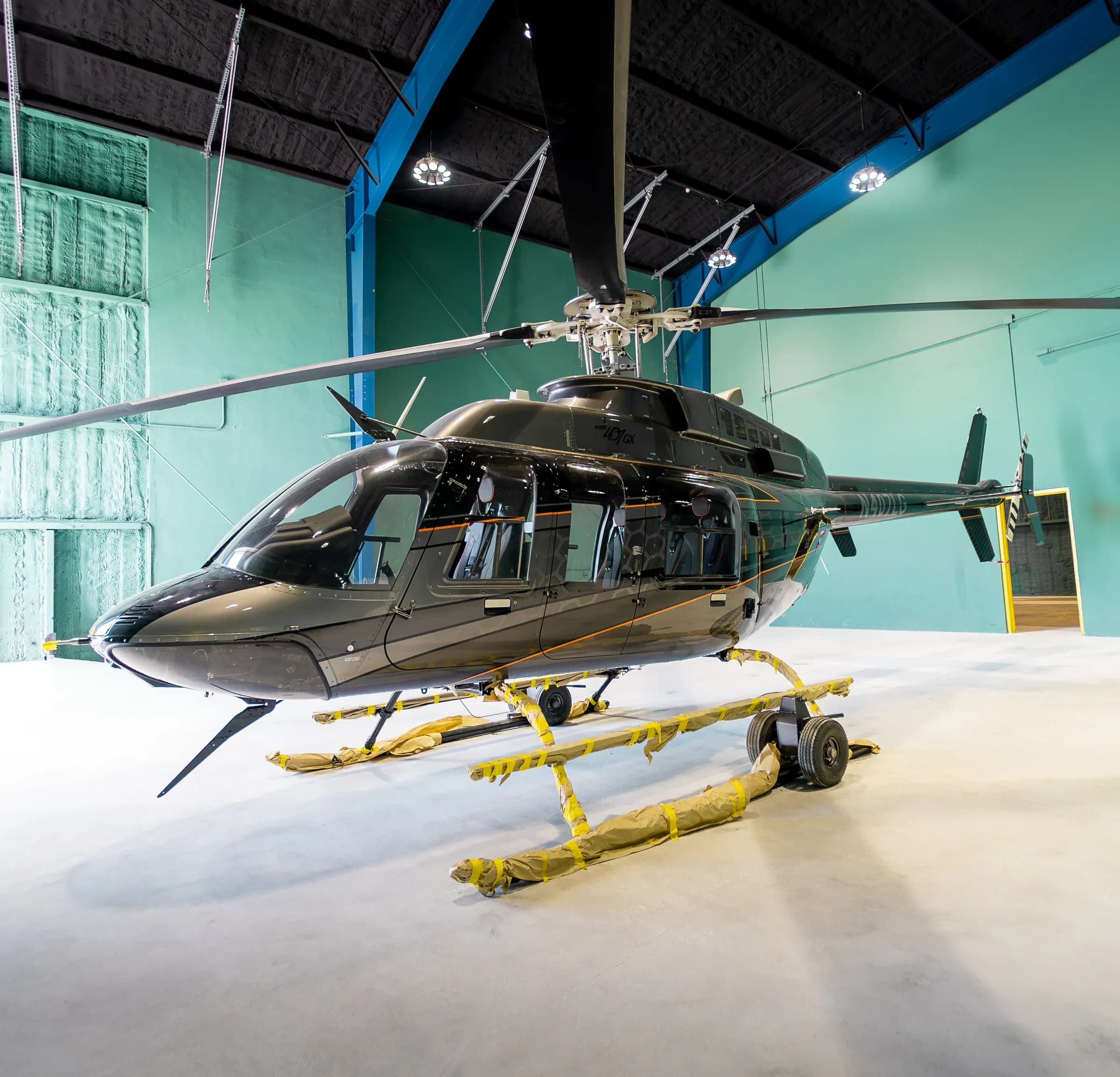 Front-side exterior view of the dark Bell 407 inside a hangar.