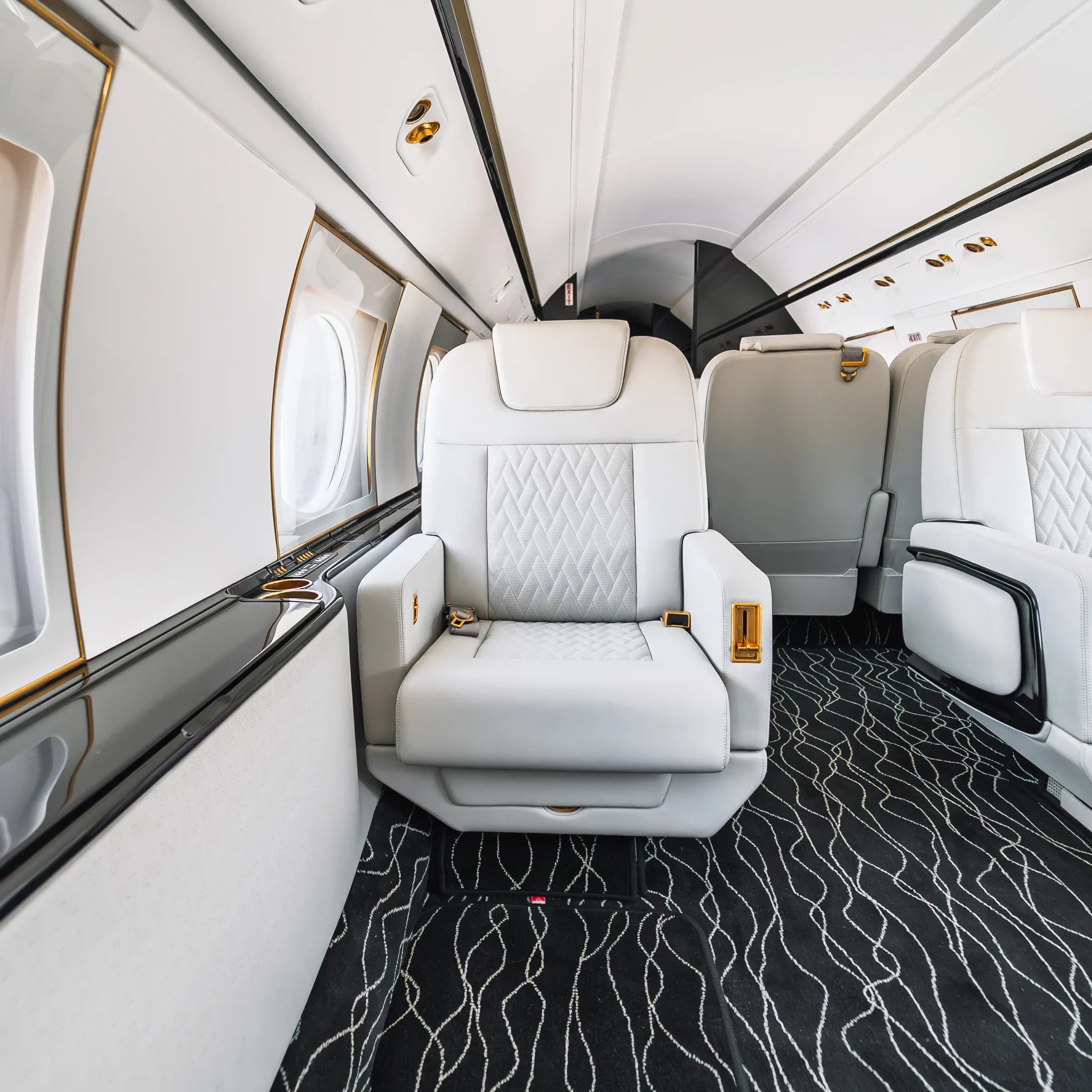 White diamond-quilted Gulfstream G550 seat beside an oval cabin window.