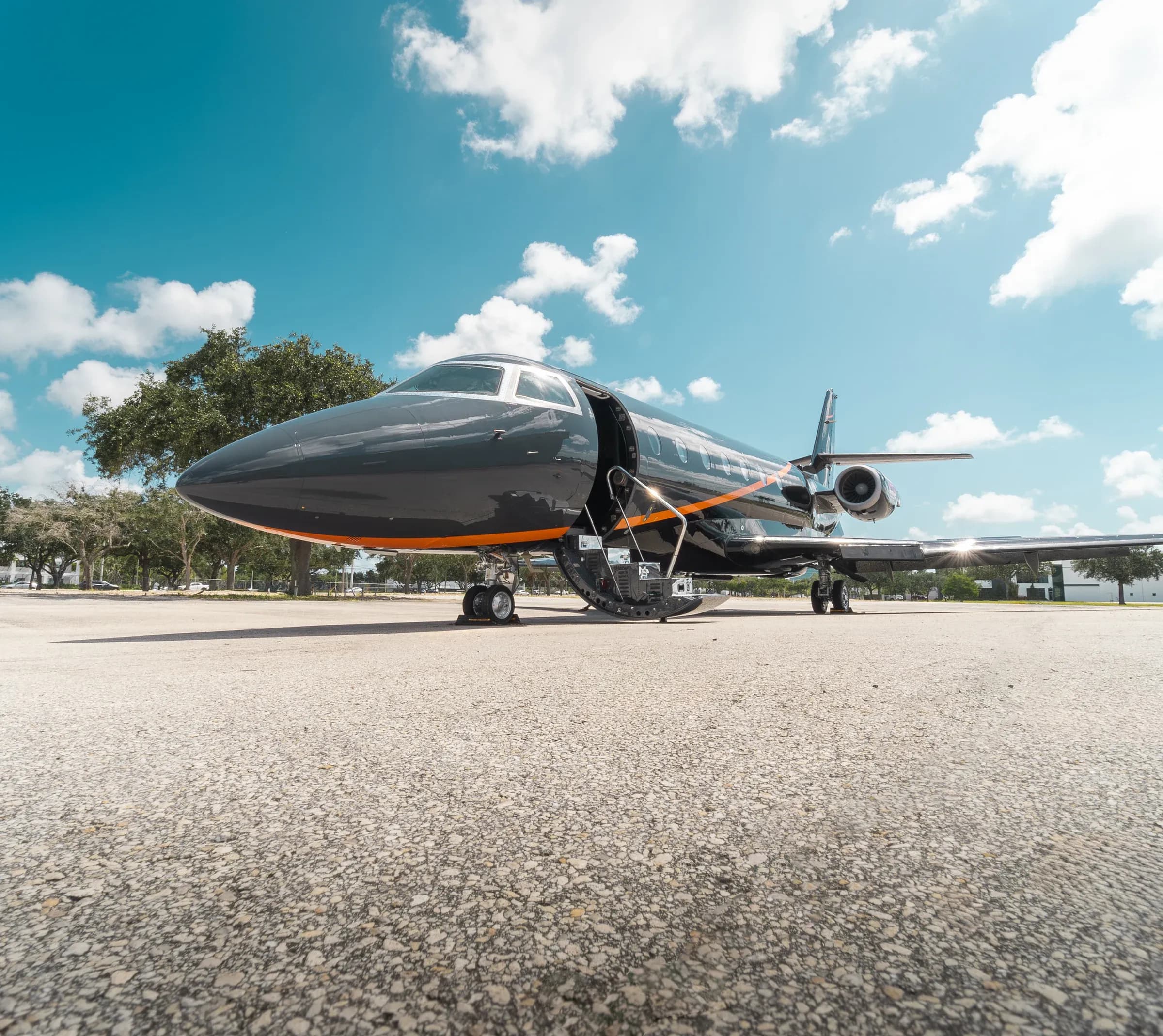 Low front three-quarter view of the dark Gulfstream G200 exterior on the ramp.