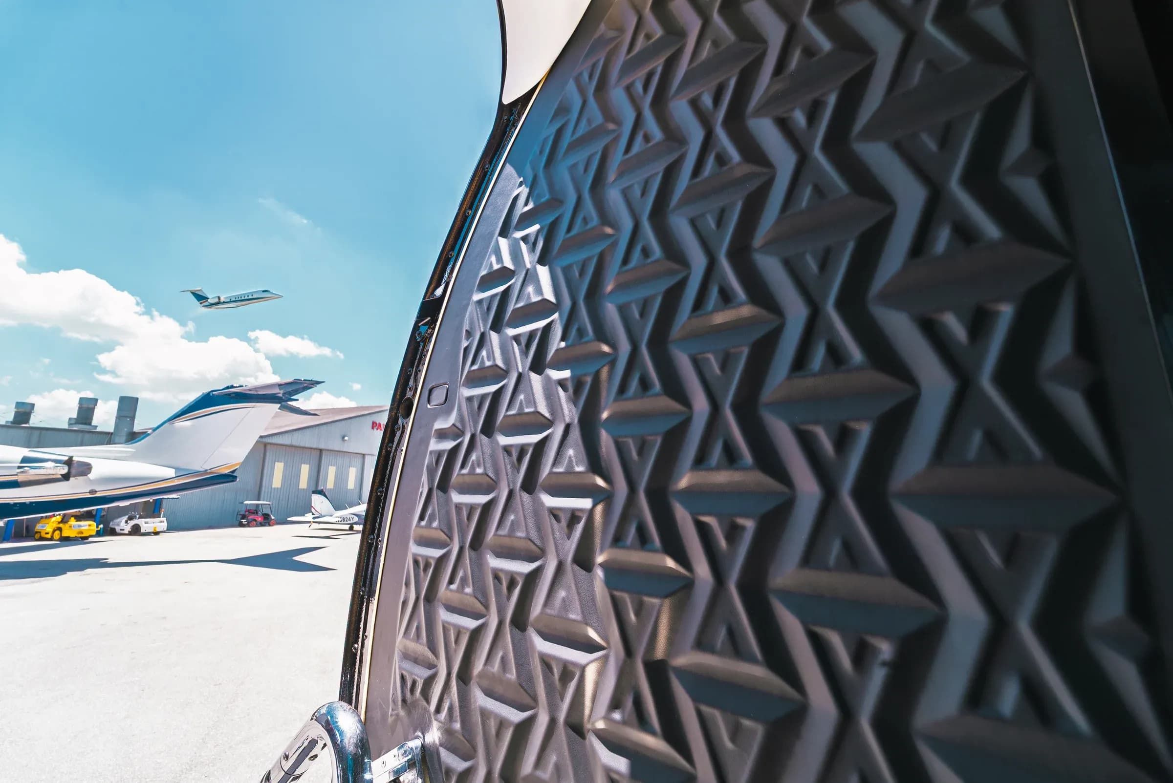 Close view of the dark faceted geometric panel at the Gulfstream G550 entrance.