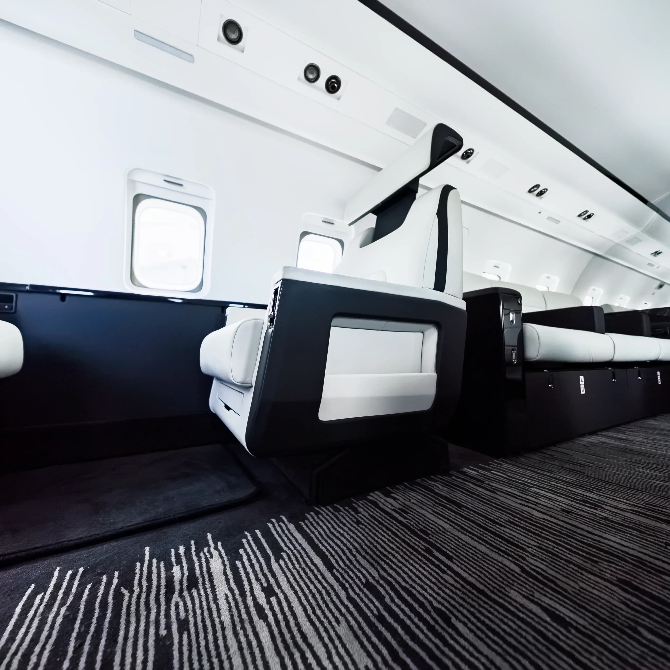 Low view of a Challenger 604 seat base above the linear-pattern cabin carpet.