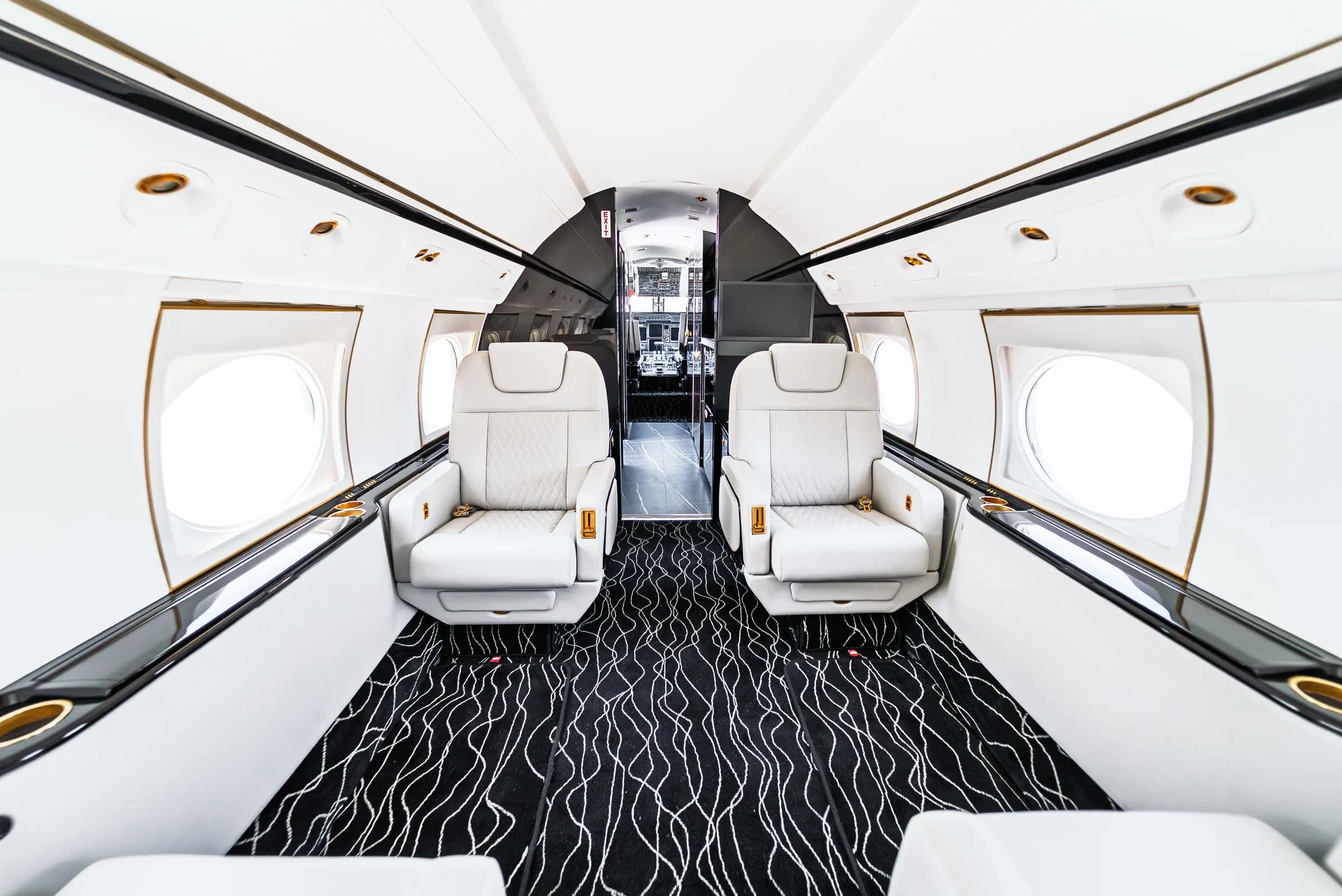 Centered Gulfstream G550 cabin view with forward seating and wavy patterned carpet.