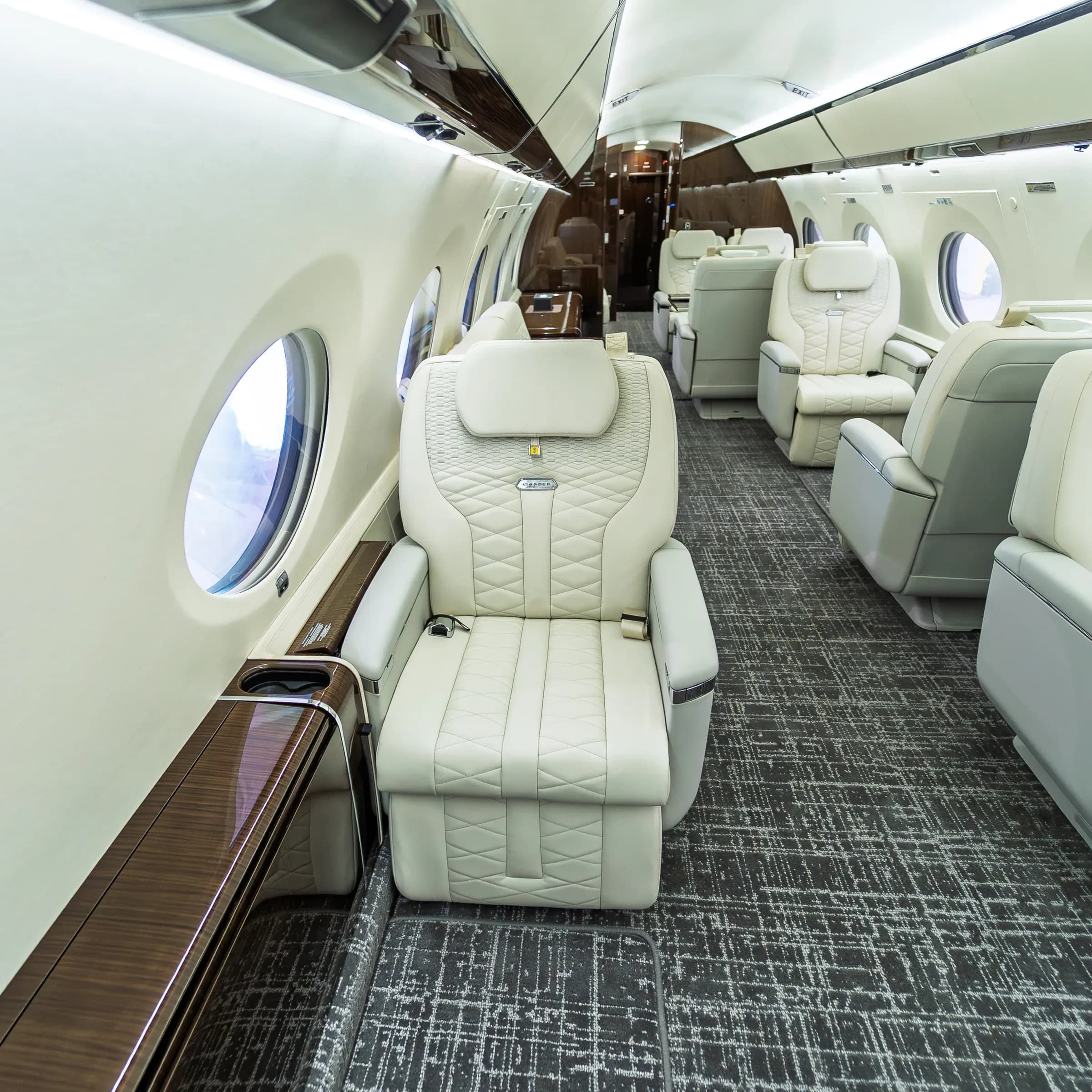 Ivory diamond-quilted Gulfstream G650ER seat beside a wood side ledge.