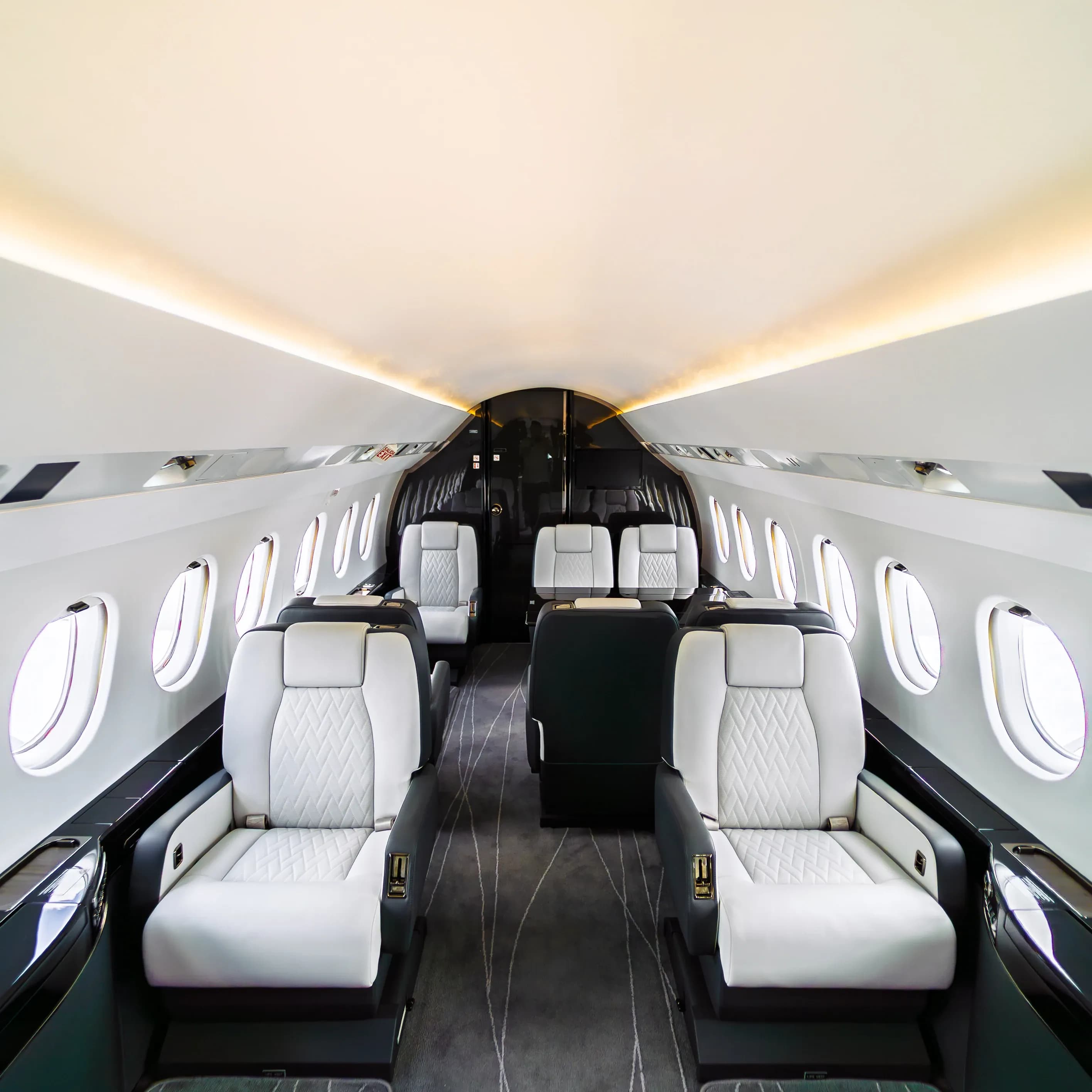 Centered Falcon 2000 cabin view with ivory seats and warm light along the overhead panels.