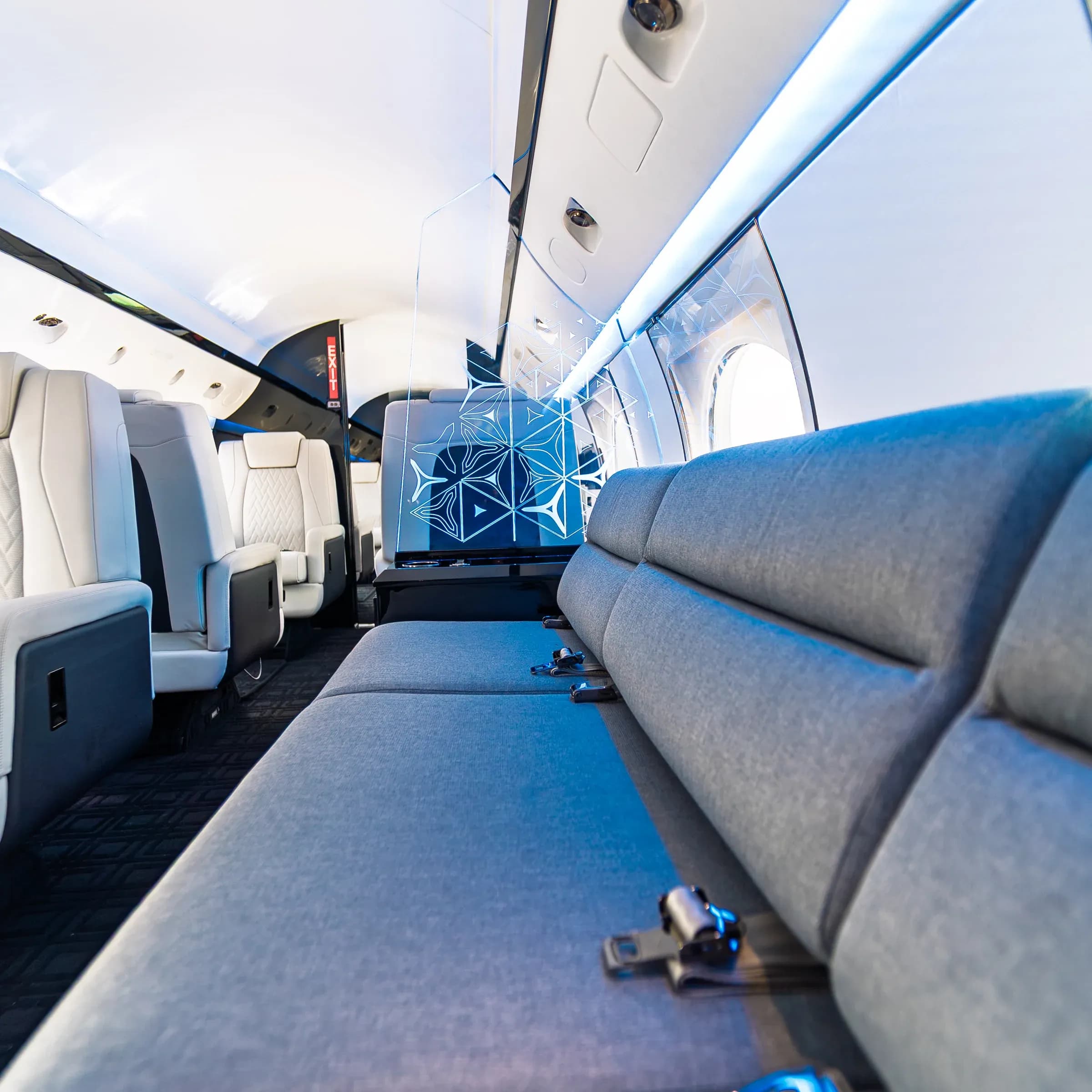 Blue Gulfstream G-IV divan beside an illuminated geometric partition.