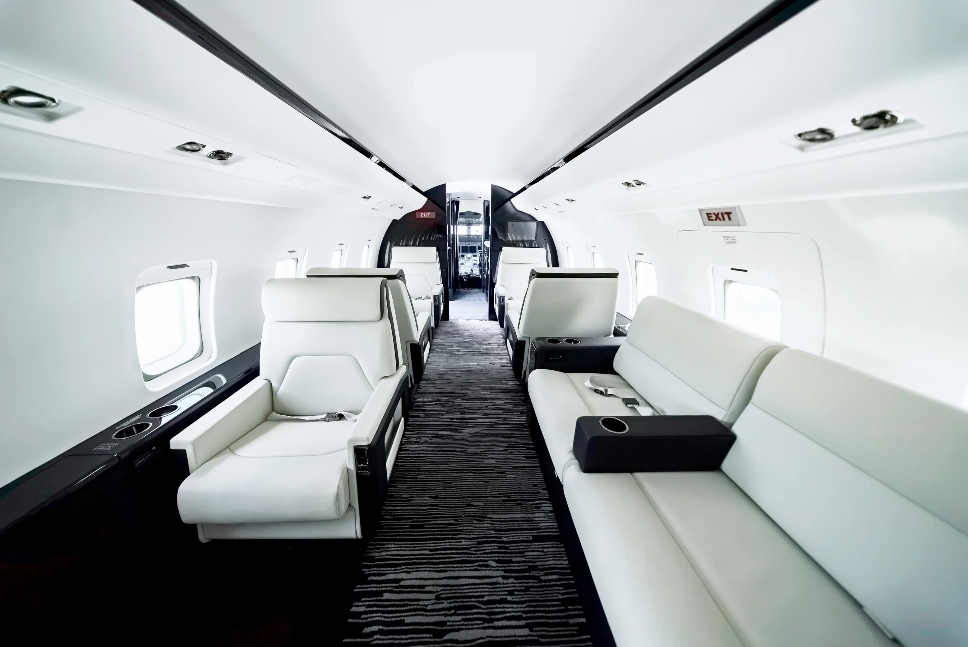 Challenger 604 cabin looking toward the entrance, with ivory seating and a long upholstered divan.