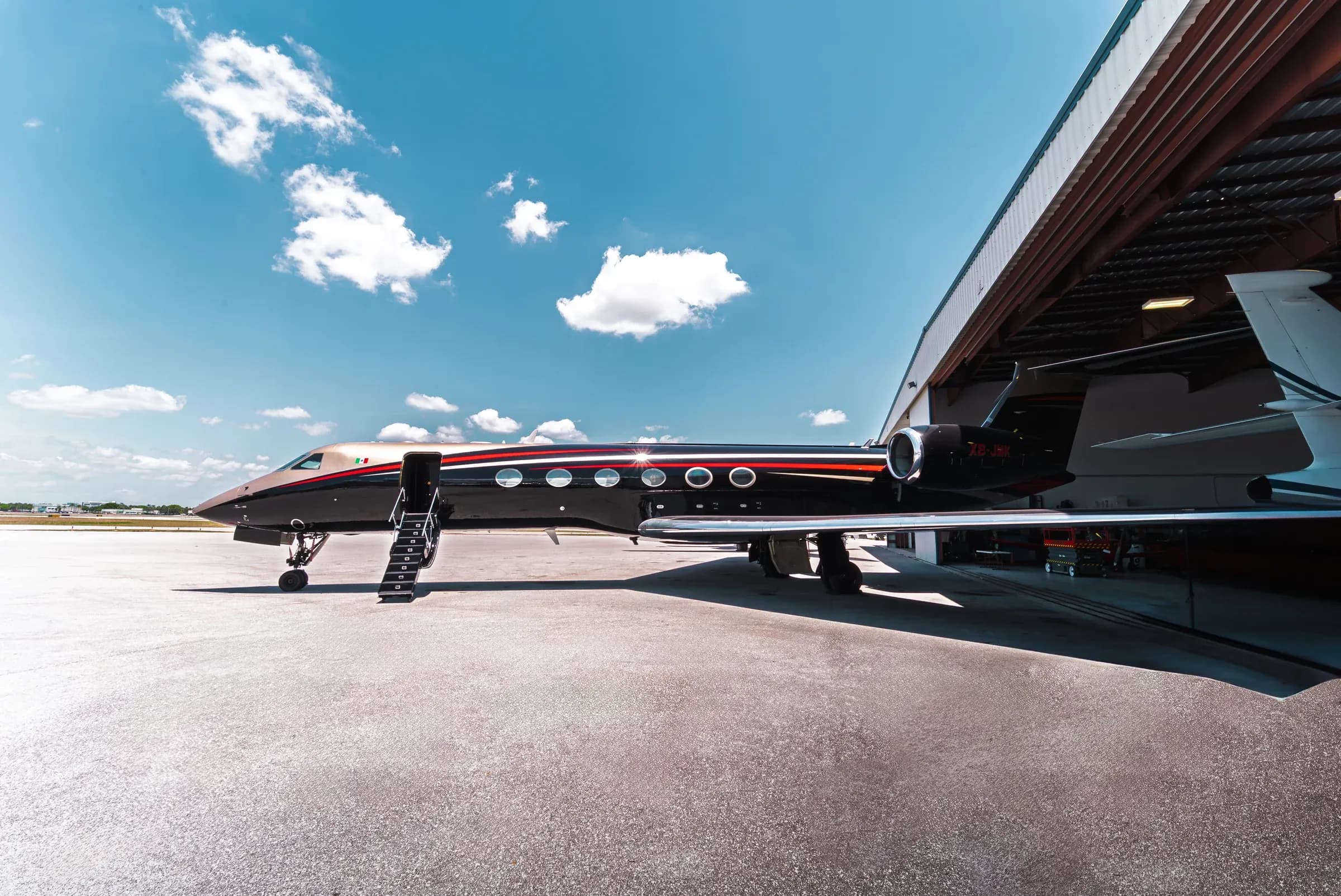 Gulfstream G550 exterior with open stairs beside an airport hangar.
