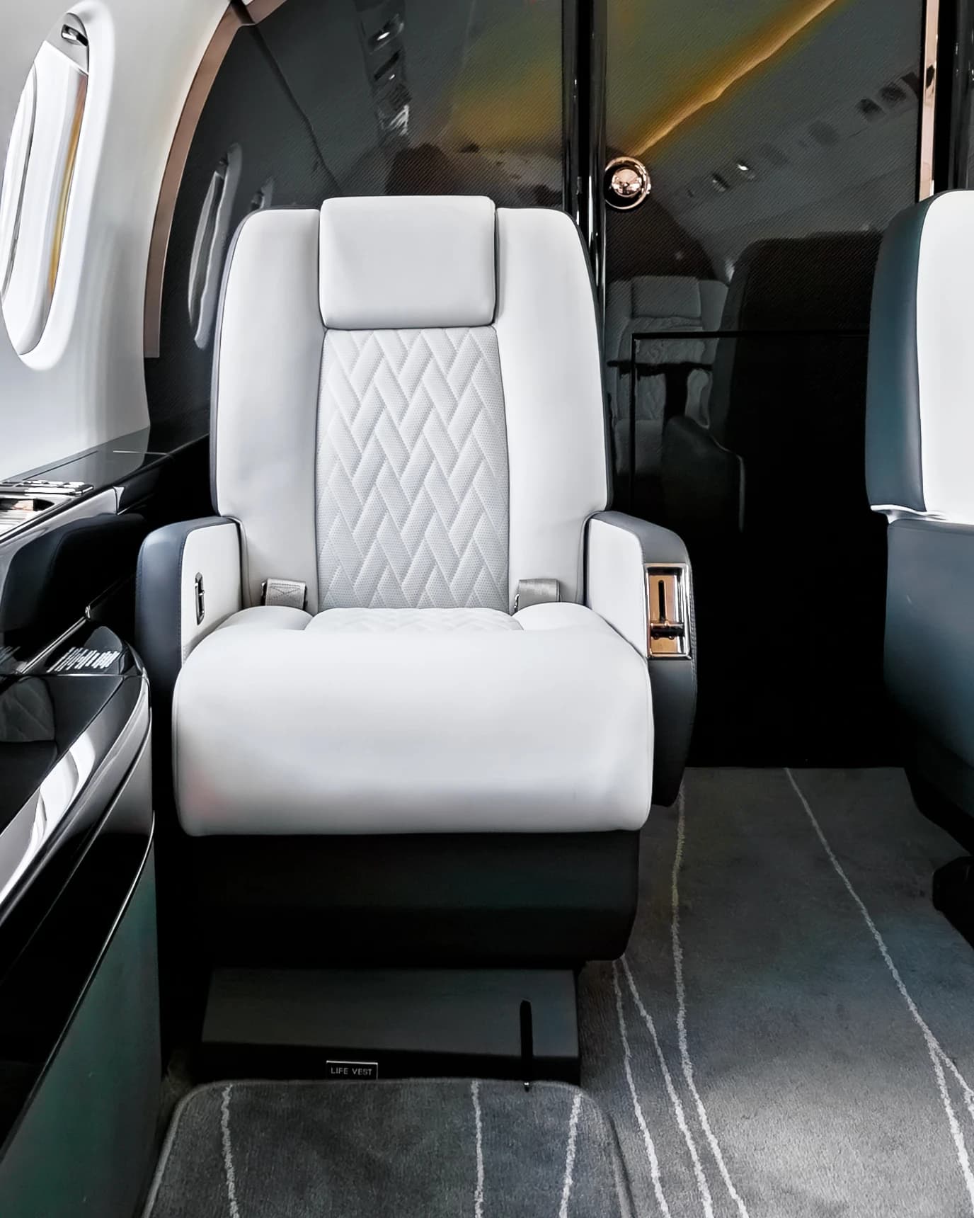 Frontal detail of an ivory Falcon 2000 seat with diamond quilting, dark armrests and a warm-lit partition.