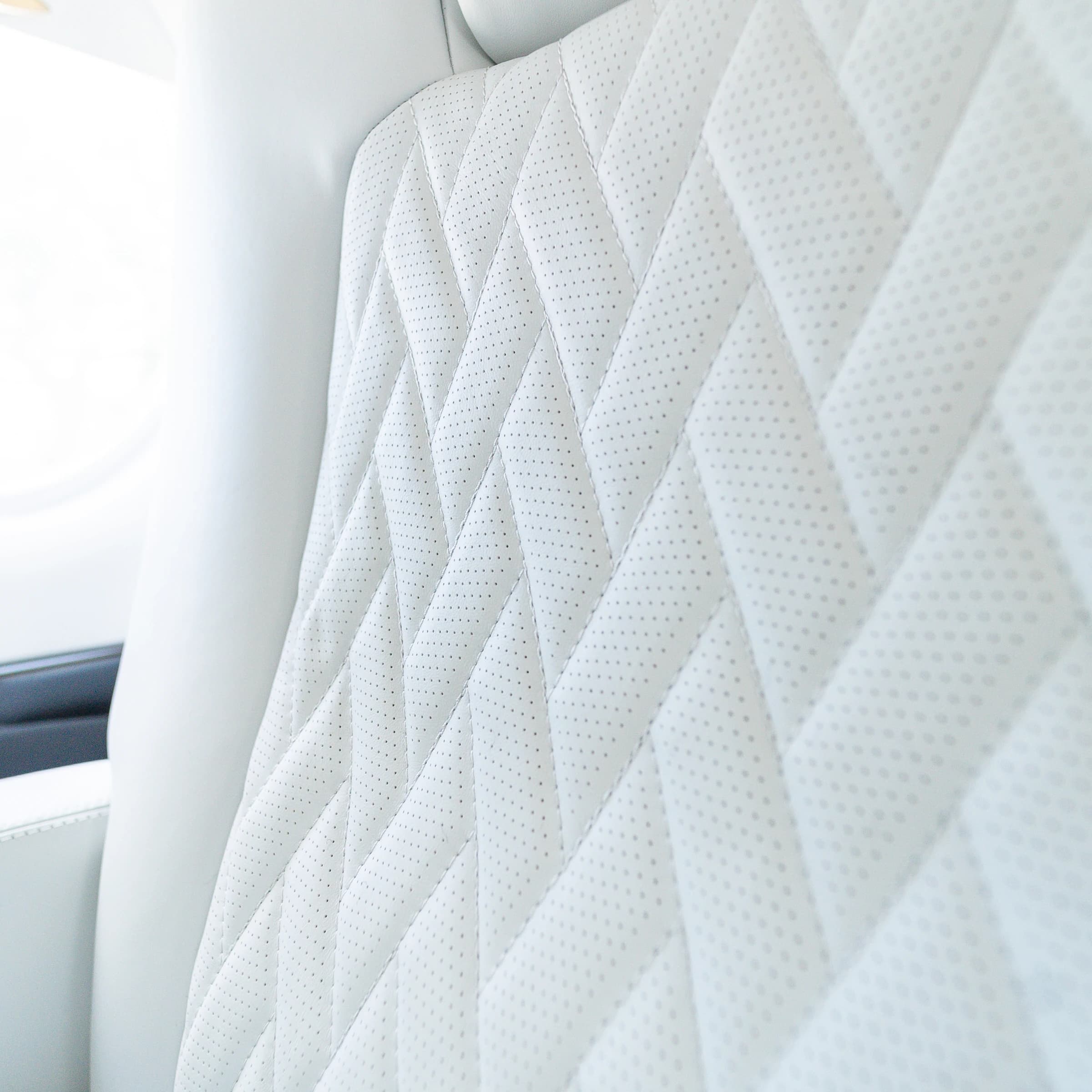 Original diamond stitching and fine perforations on the Gulfstream G200 ivory seat back.
