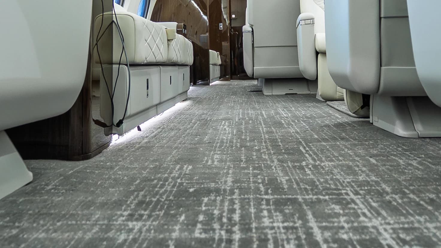 Original Gulfstream G650ER gray patterned carpet running between upholstered seat bases.