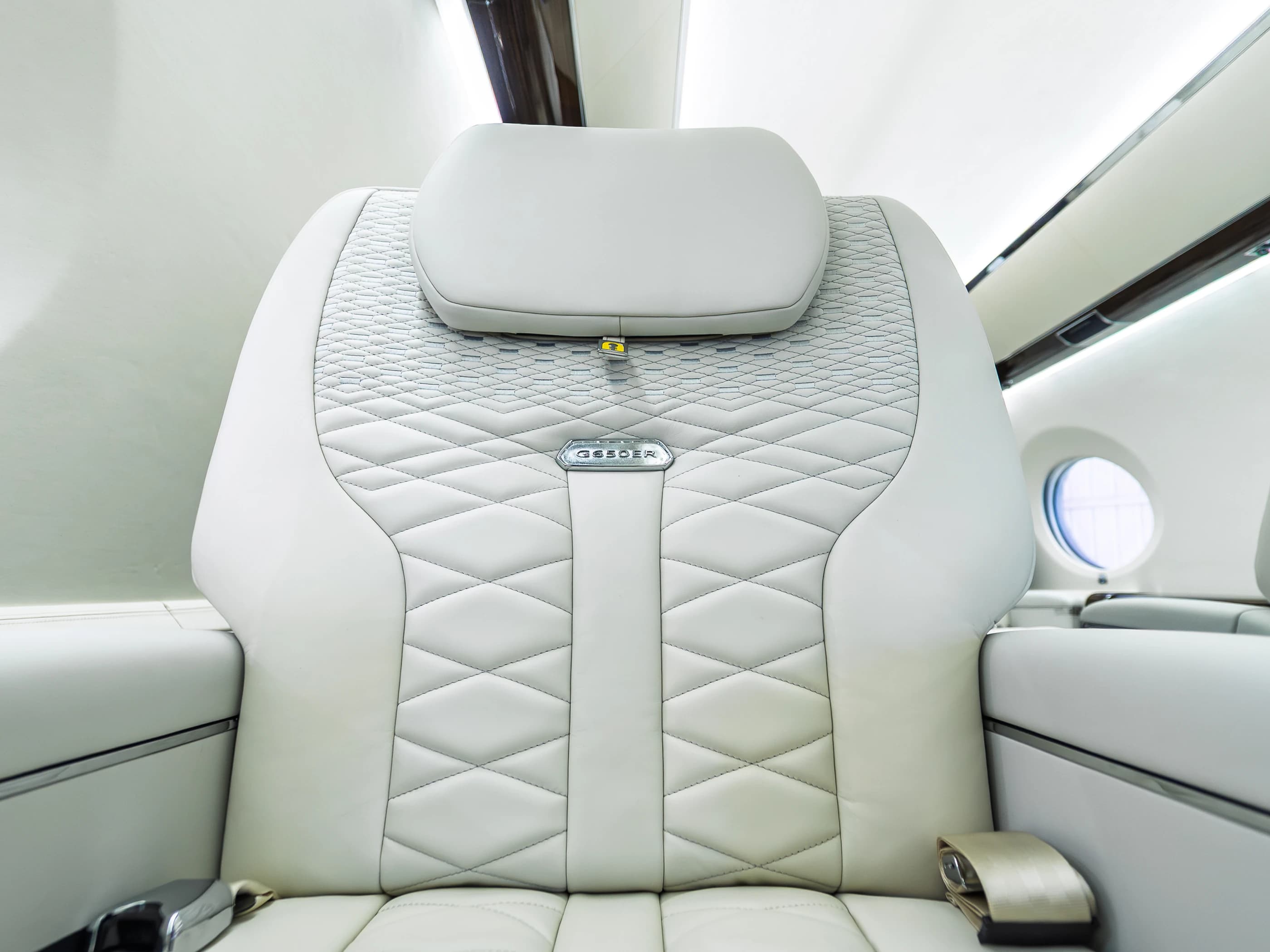 Gulfstream G650ER seat back with its original graduated diamond stitching, headrest and metal badge.