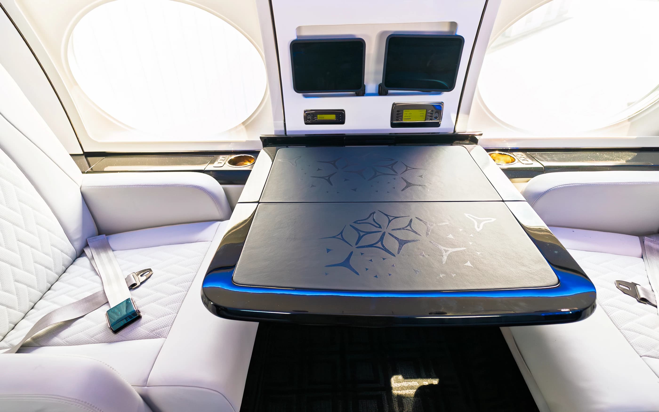 Original Gulfstream GIV table with geometric surface detailing and blue edge lighting between ivory upholstered seats.