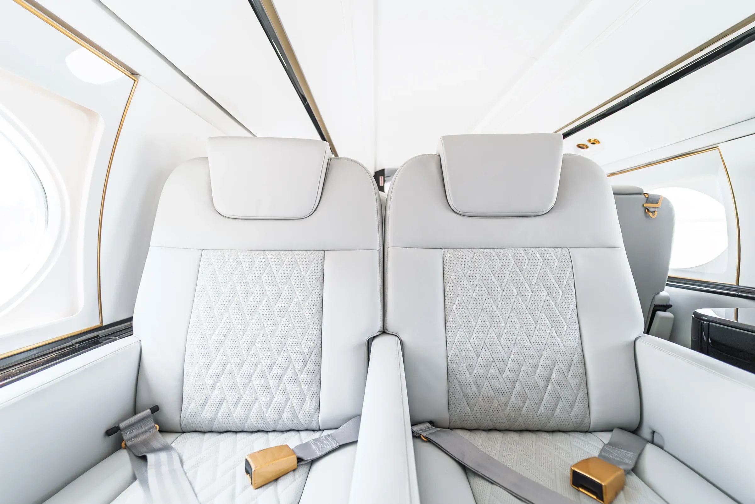 White Gulfstream G550 seat backs and quilted inserts with gold-tone belt fittings.
