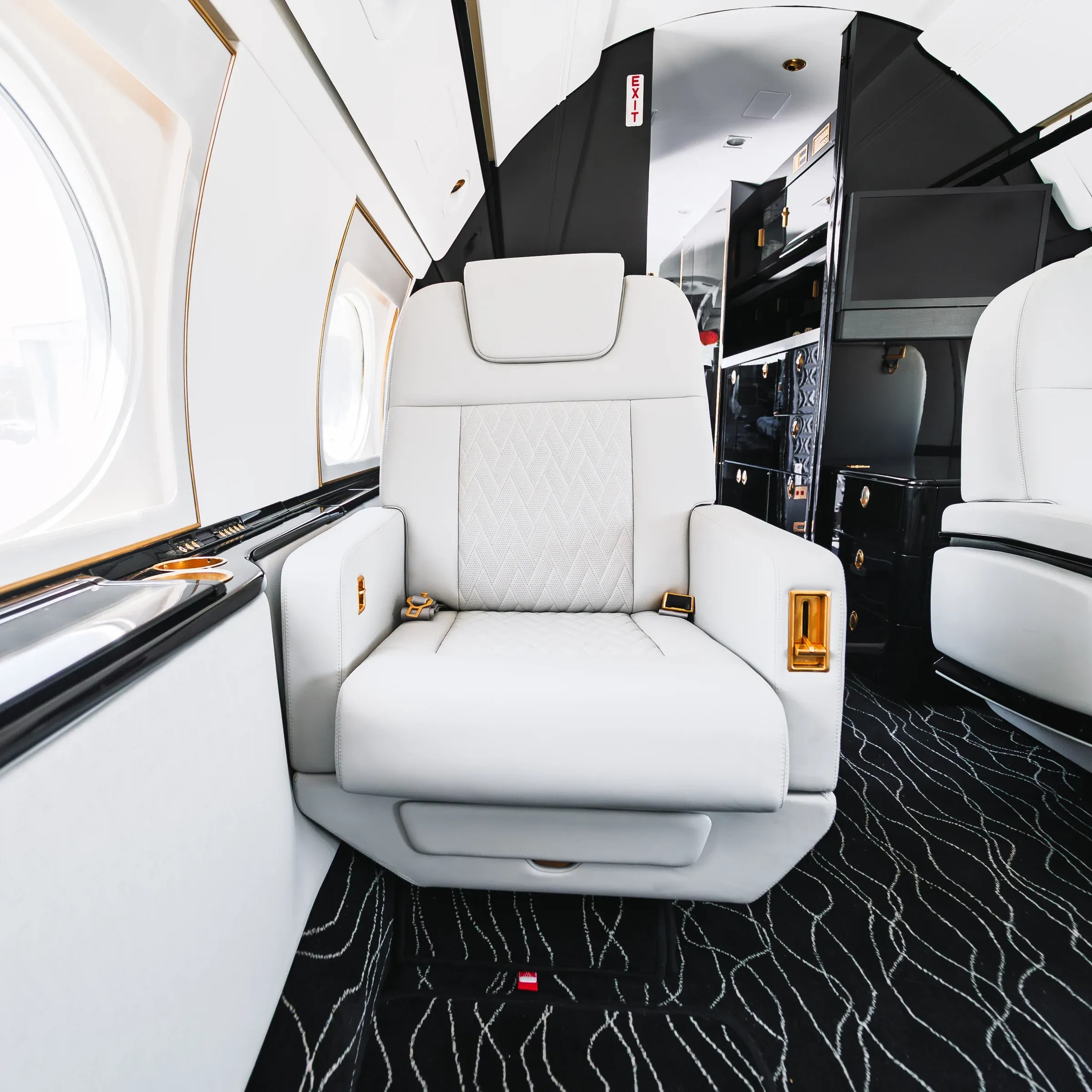 White quilted Gulfstream G550 seat with dark arm trim and gold-tone controls.