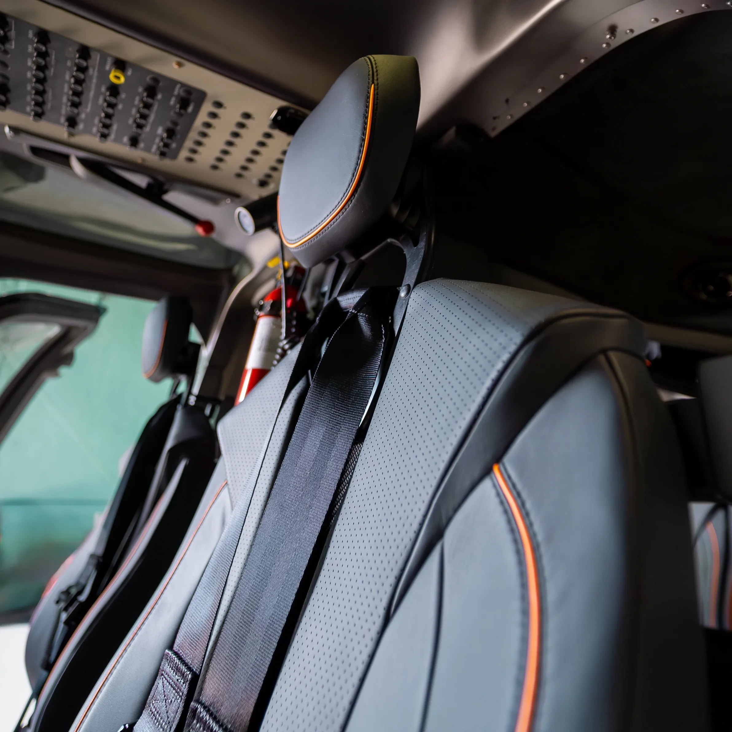 Close view of a dark Bell 407 seat back with orange piping and woven-pattern trim.