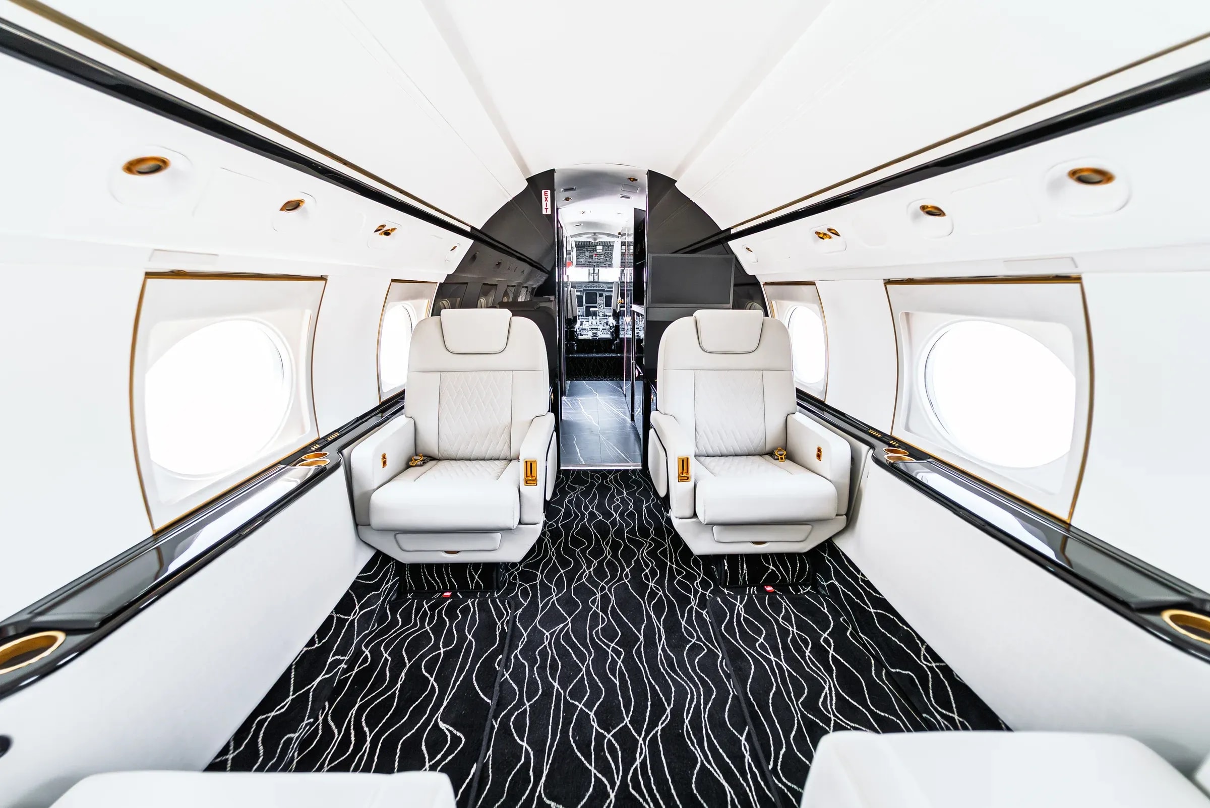 Centered Gulfstream G550 cabin view with forward seating and wavy patterned carpet.