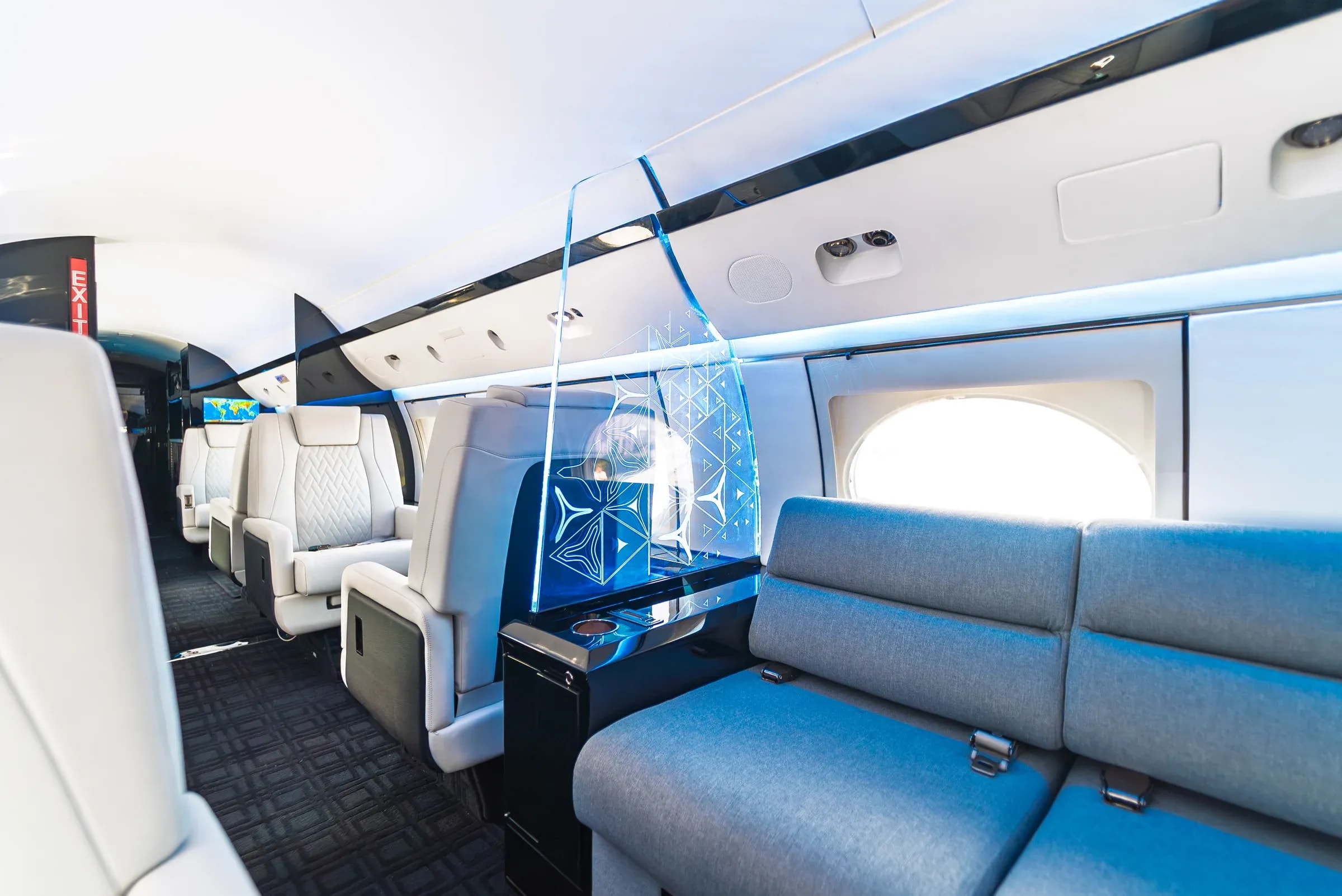 Gulfstream G-IV cabin with white quilted seats, a blue divan and an illuminated geometric partition.