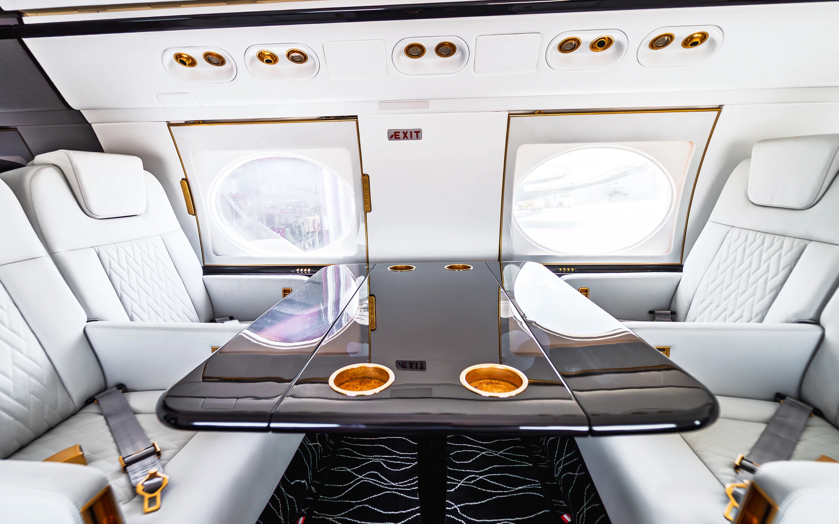 Gulfstream G550 club seating around a glossy dark table with gold-tone cup holders.