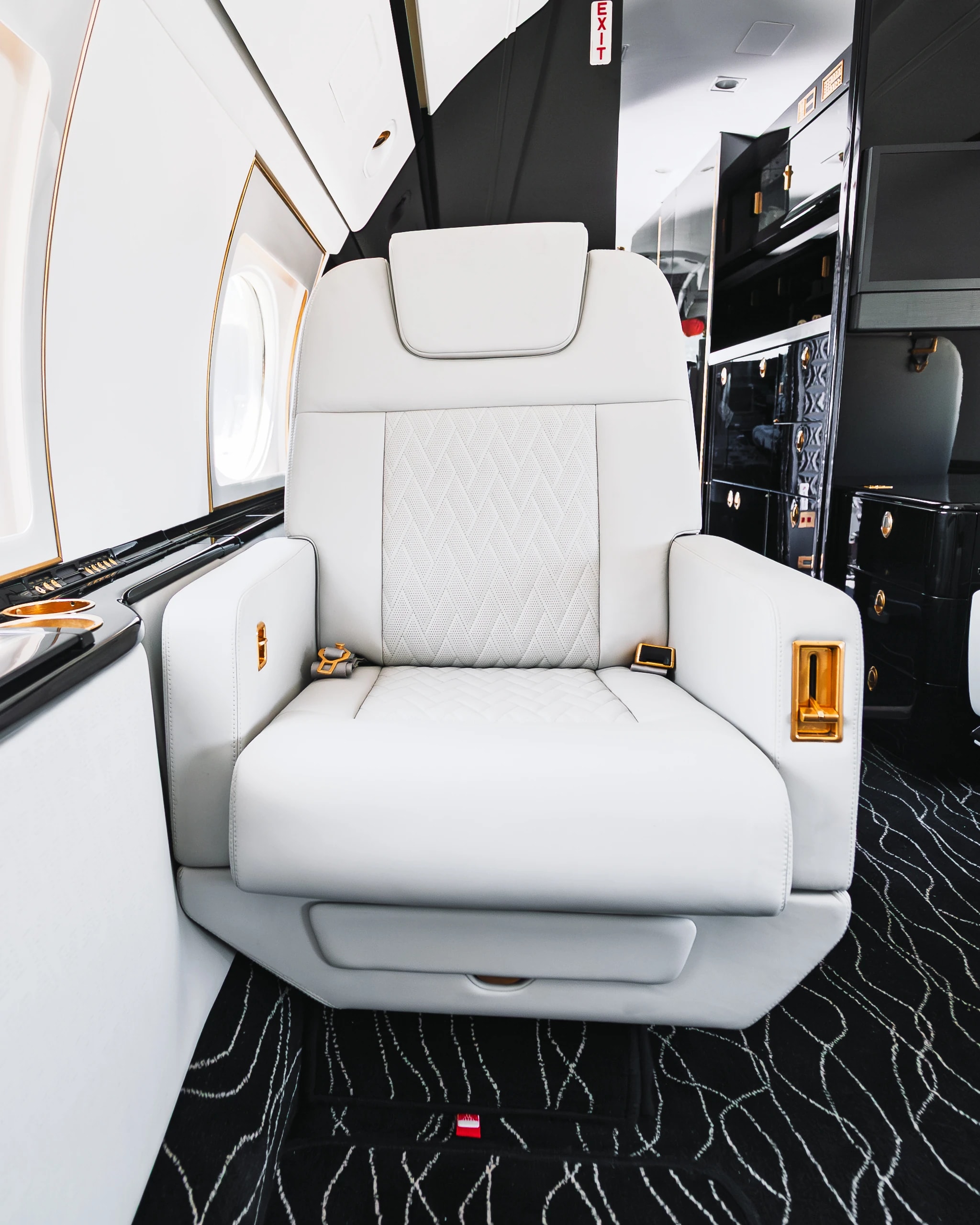 Gulfstream G550 ivory seat with its original quilted insert, gold-tone controls and dark surrounding trim.