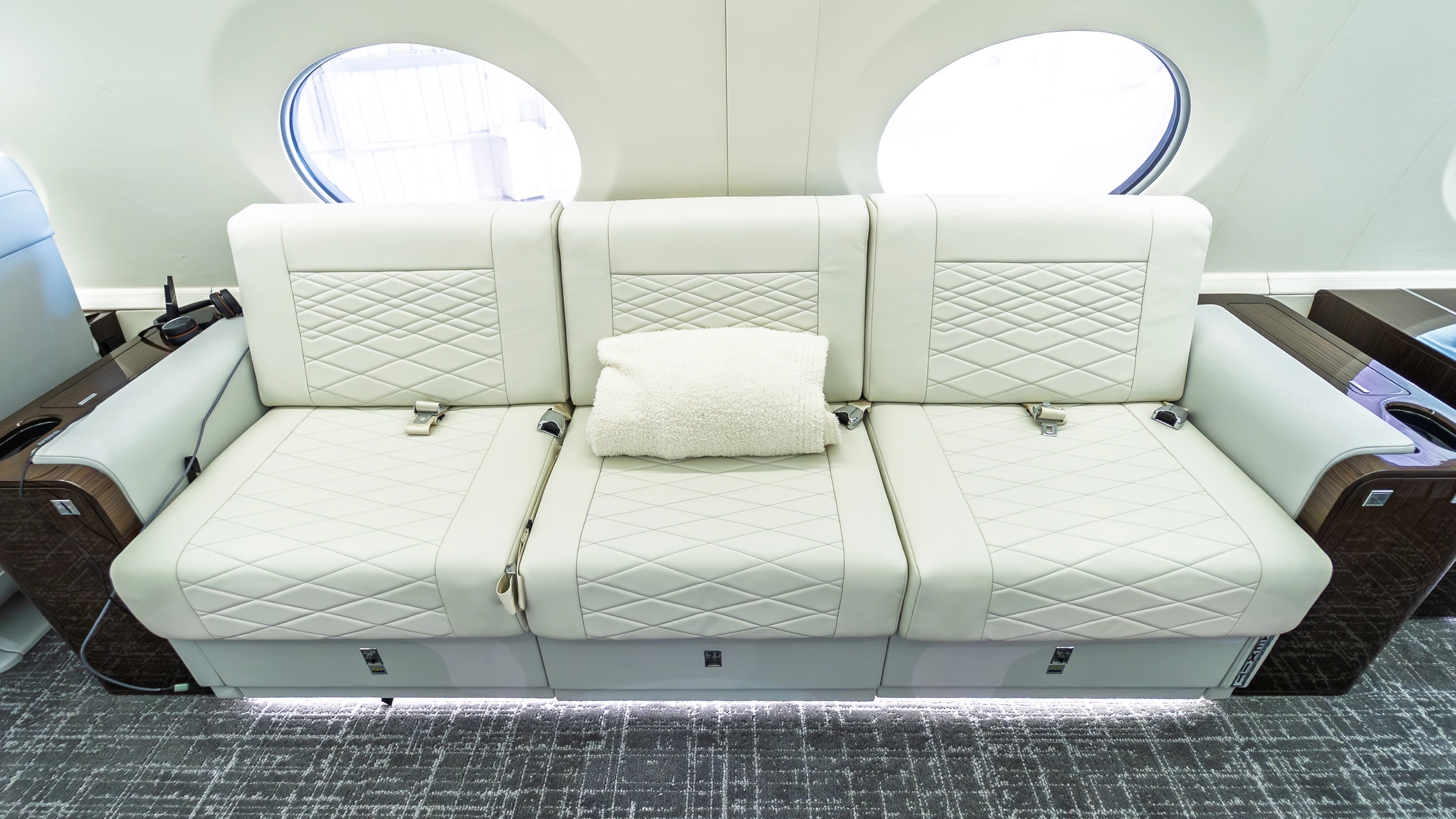 Frontal view of the Gulfstream G650ER ivory divan with three original seat belts and a center pillow.